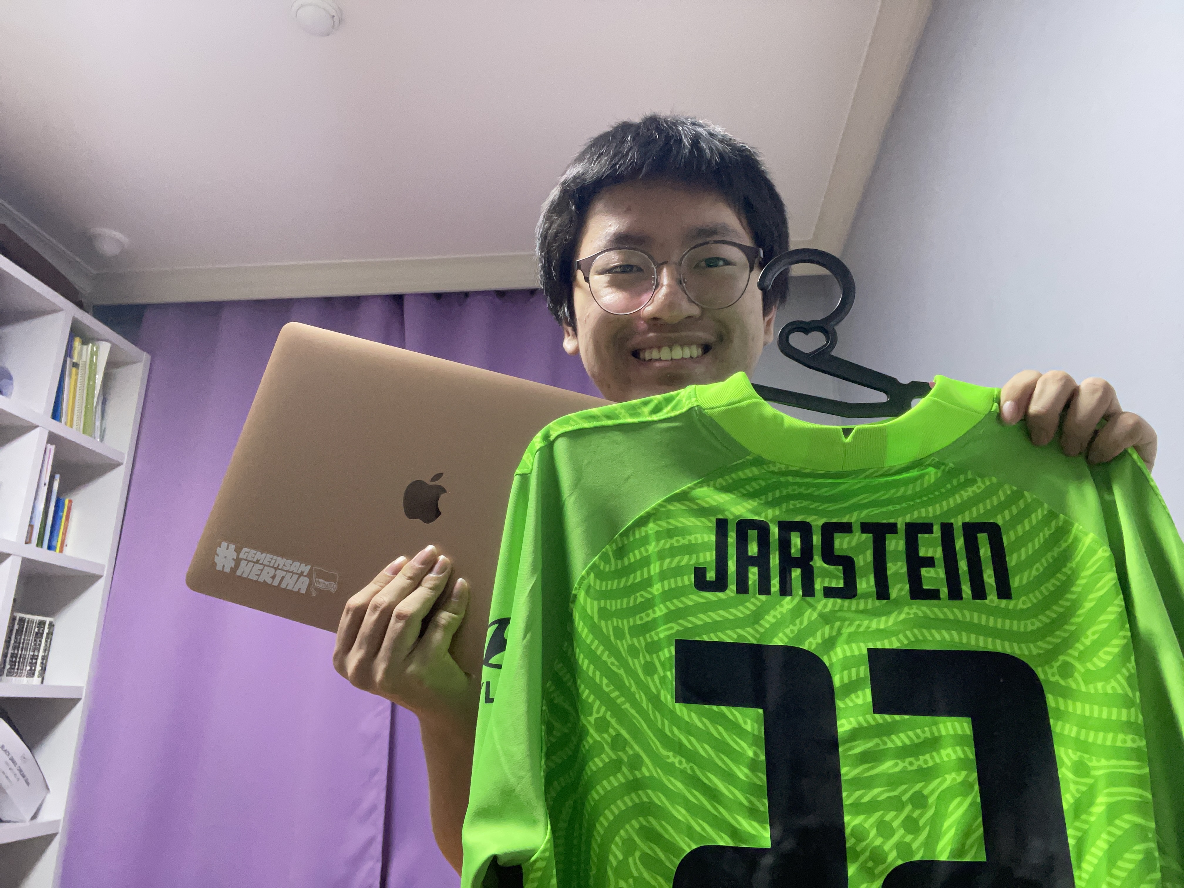 Doyeong Choi mit seinem Jarstein Trikot und seinem Laptop auf dem ein Hertha-Sticker klebt.