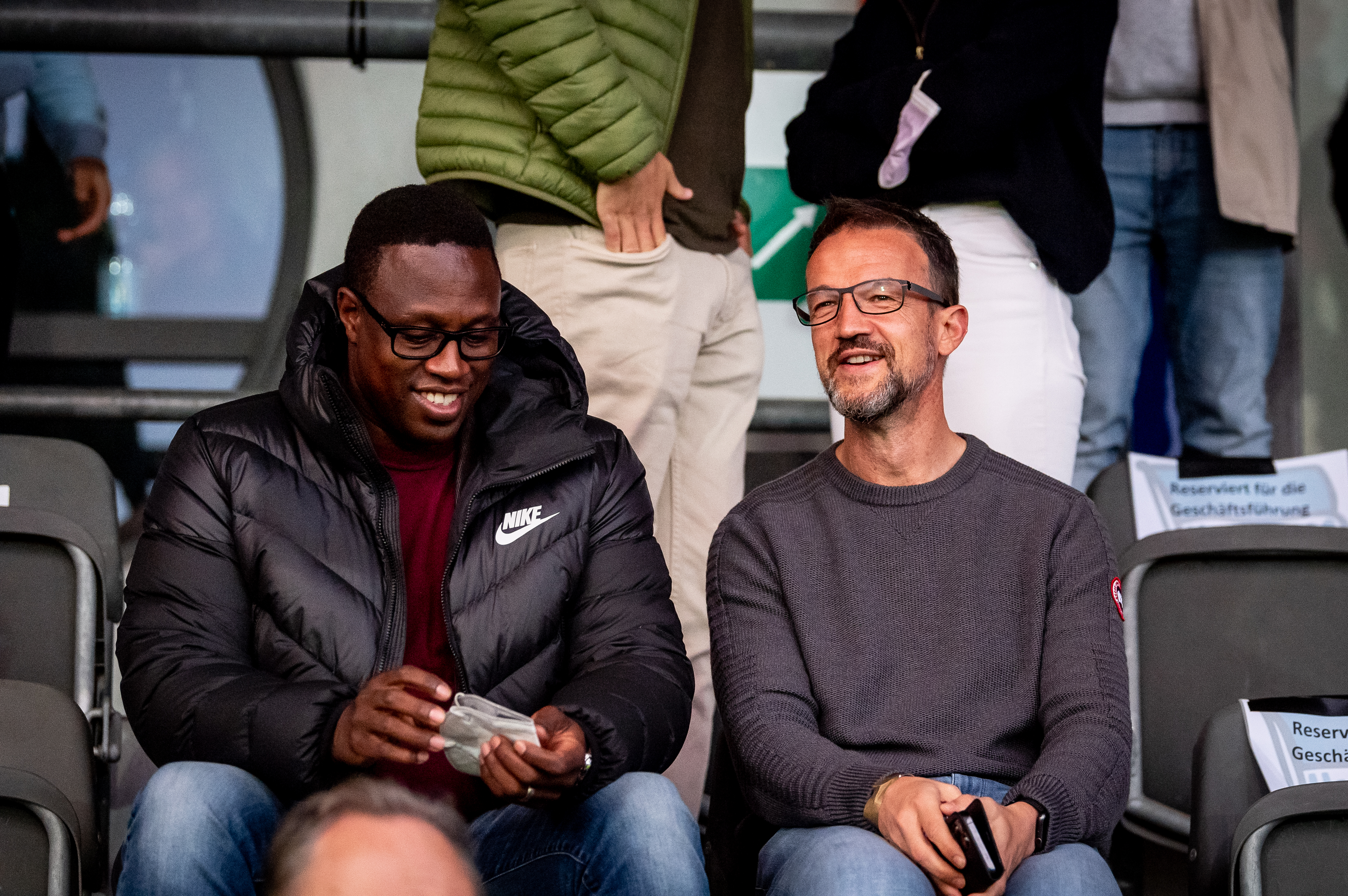 Pablo Thiam (li.) und Fredi Bobic sitzen auf der Tribüne im Stadion auf dem Wurfplatz/Amateurstadion.