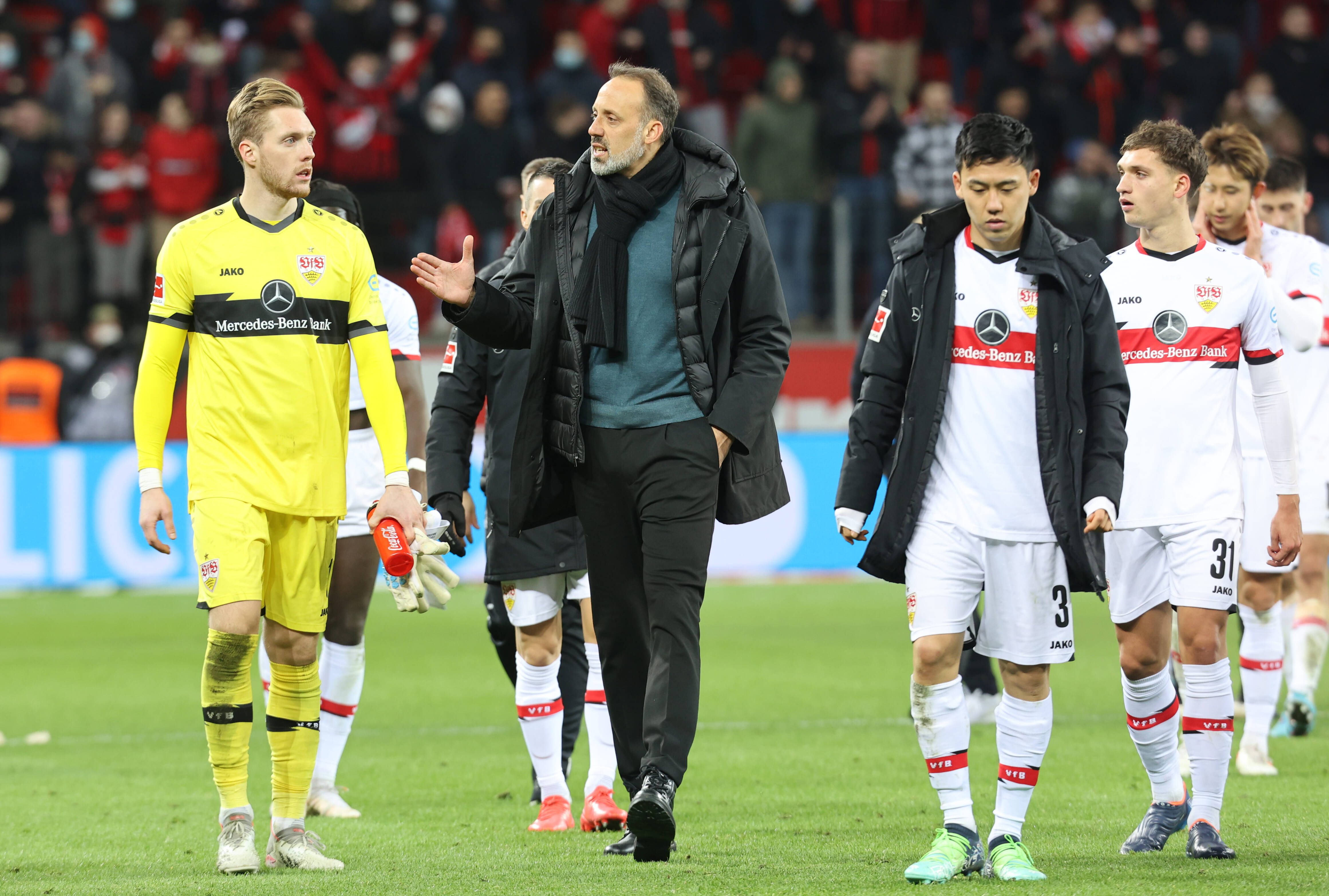 Florian Müller, Pellegrino Matarazzo y Wataru Endo sobre el césped tras un partido del Stuttgart.