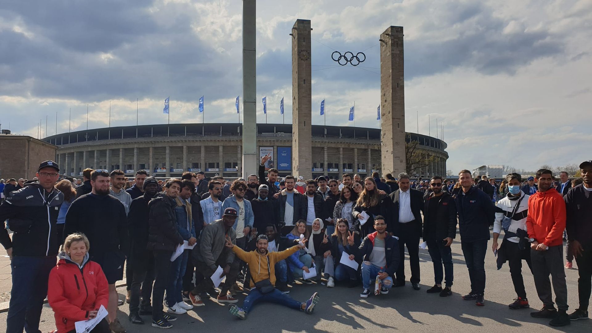 Die Geflüchteten posieren gemeinsam lächelnd vor dem Berliner Olympiastadion.