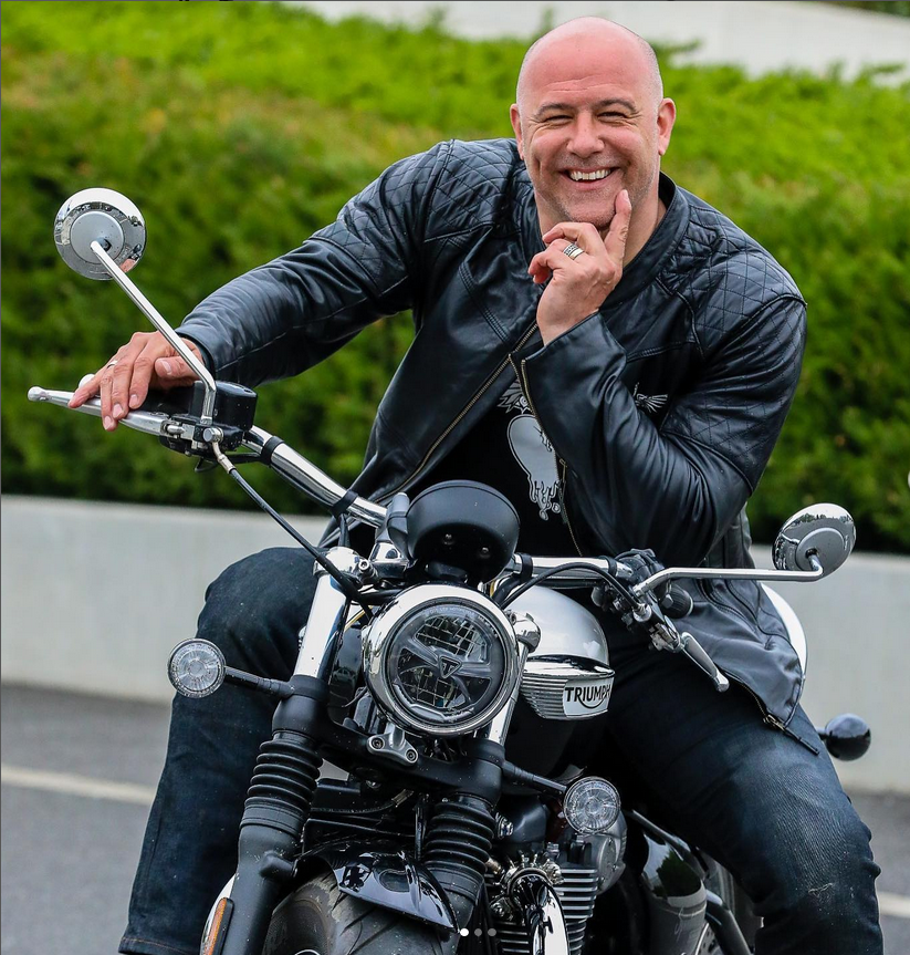 Gábor Király lächelt auf seinem Motorrad.