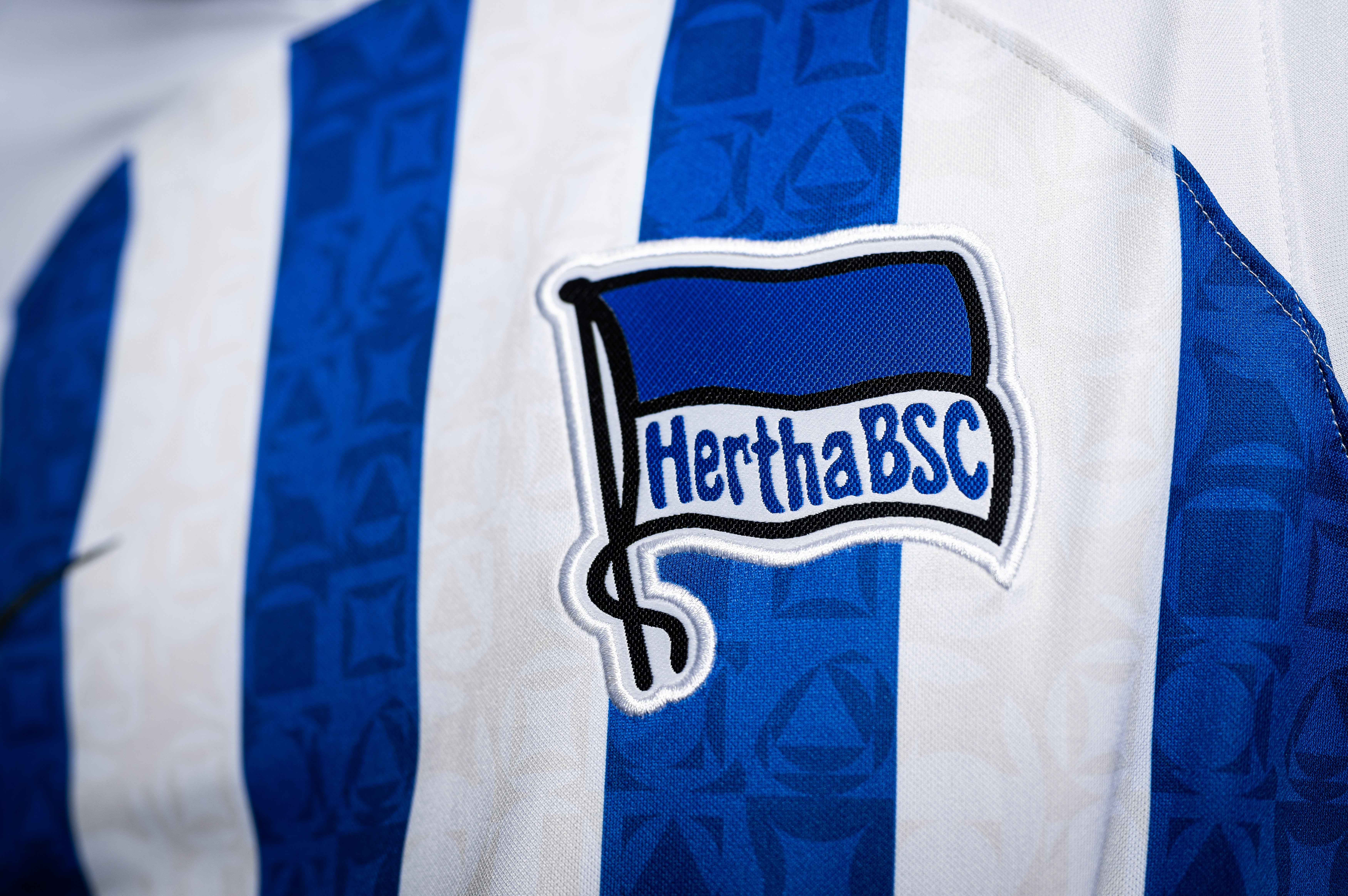 The Hertha badge on a white and blue striped home shirt from the 2022/23 season.