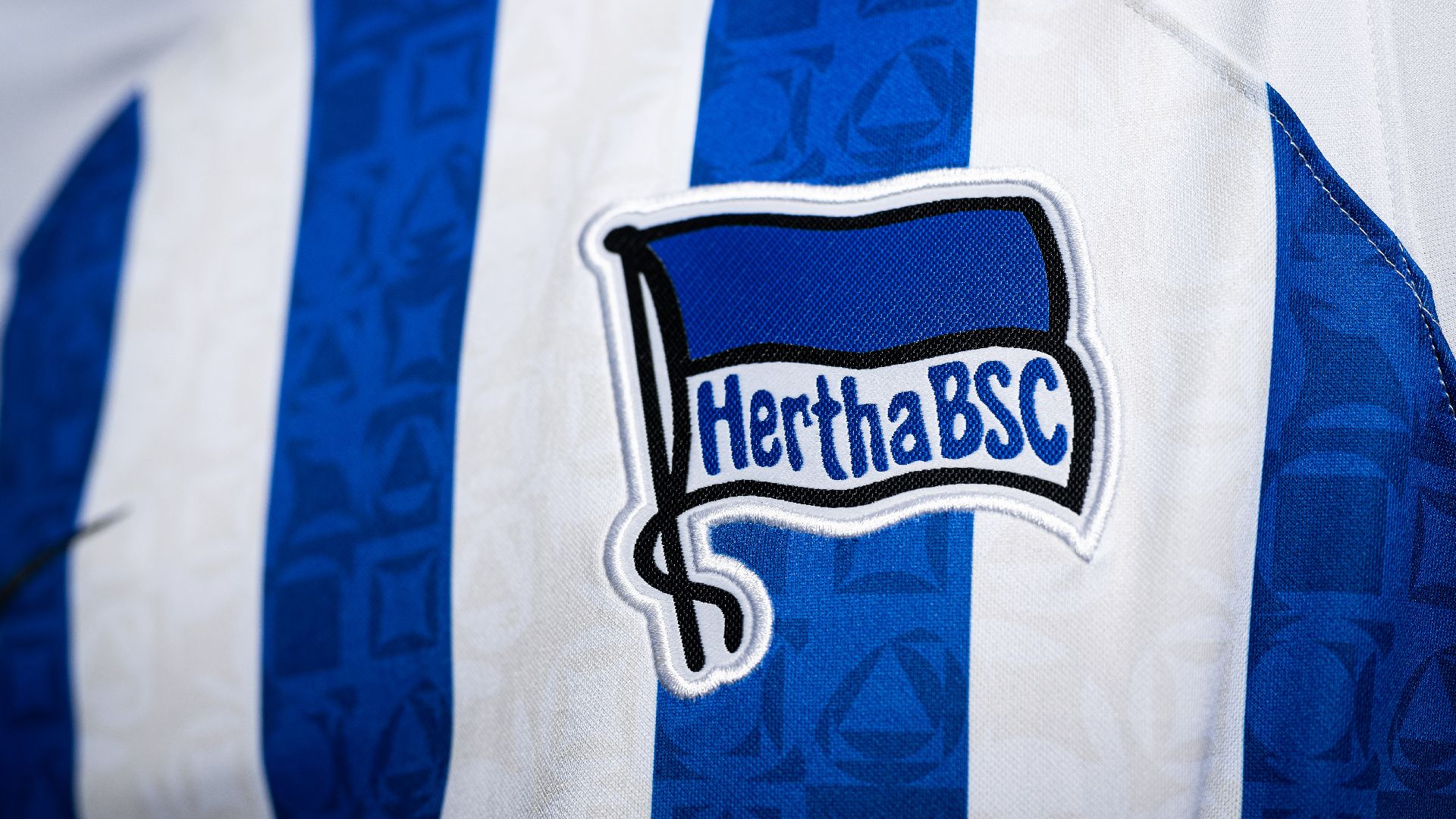 The Hertha badge on a white and blue striped home shirt from the 2022/23 season.