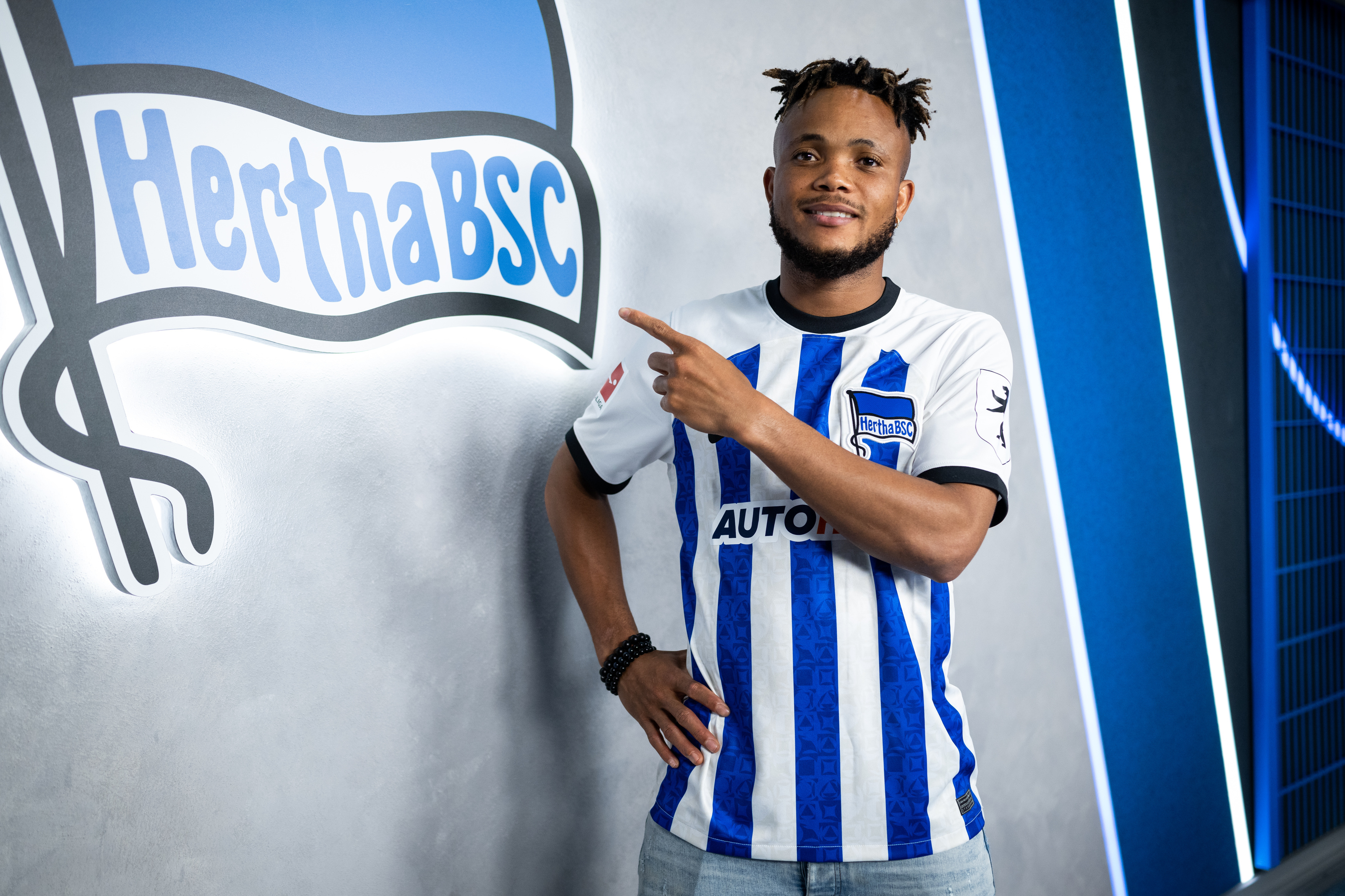 Chidera Ejuke flashes a smile in front of the Hertha badge.