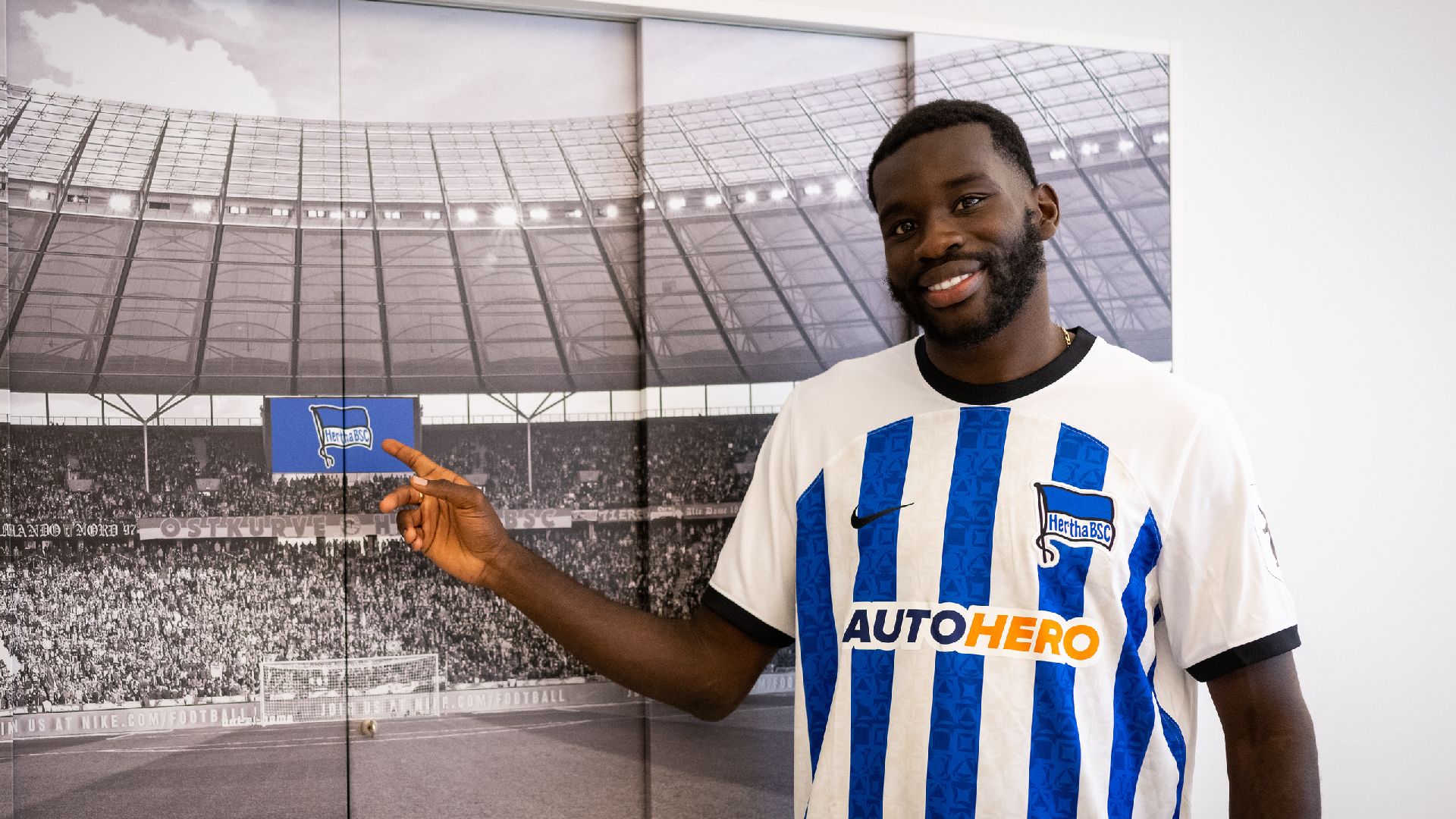 Wilfried Kanga smiles and points to the Hertha flag.