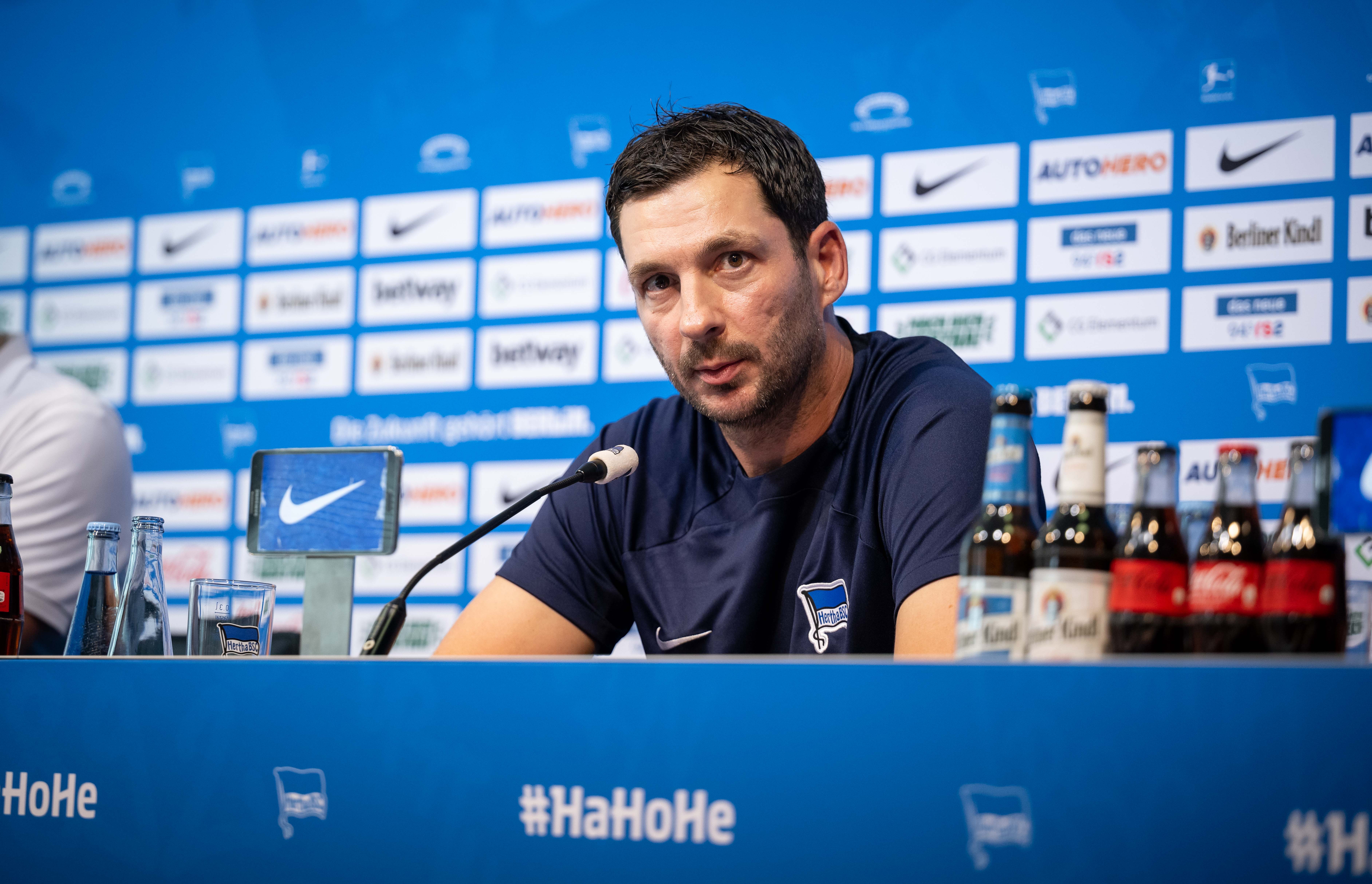 Sandro Schwarz facing journalists in the media room.