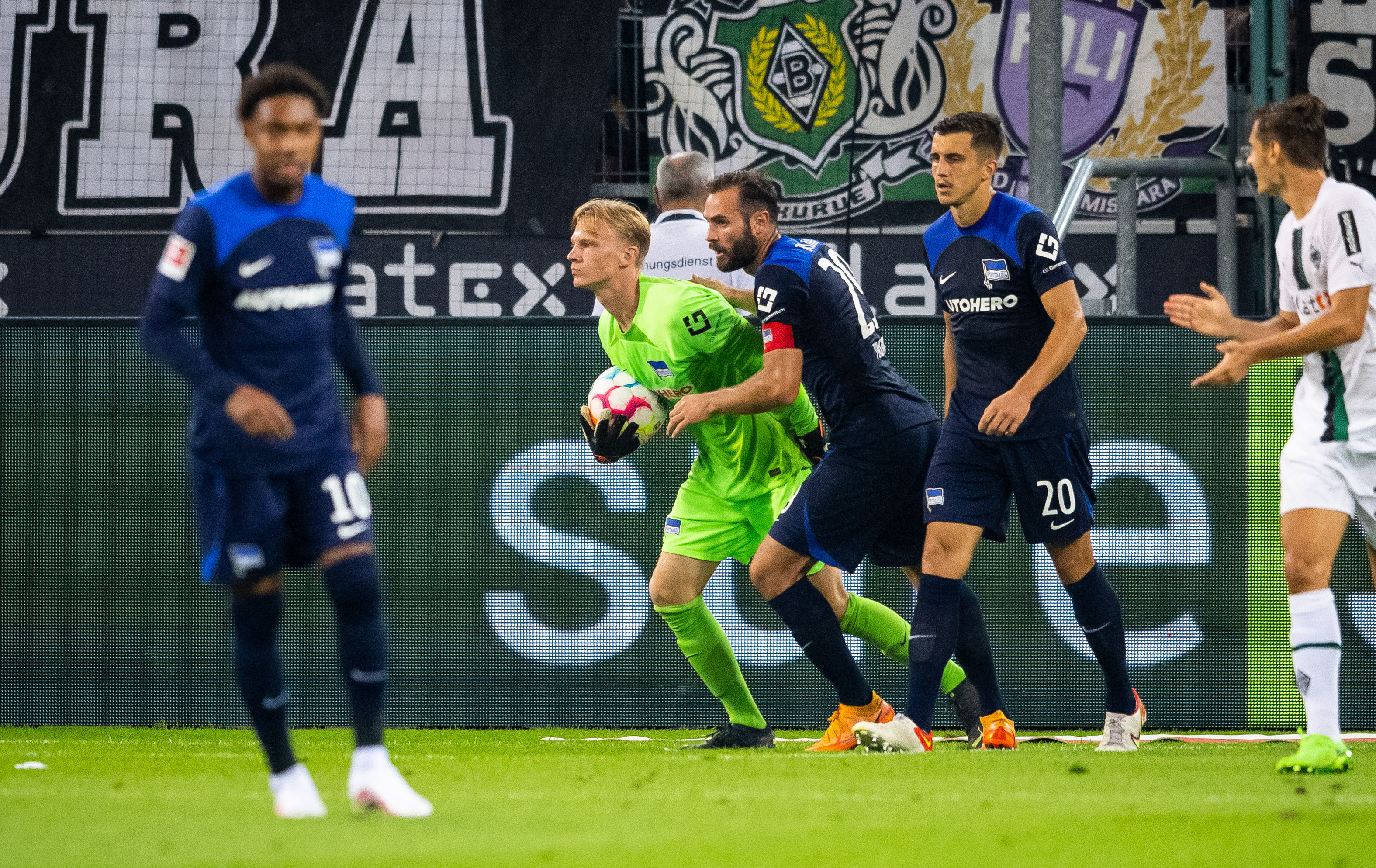 Oliver Christensen hält umringt von Teamkollegen ein Ball fest in den Händen.