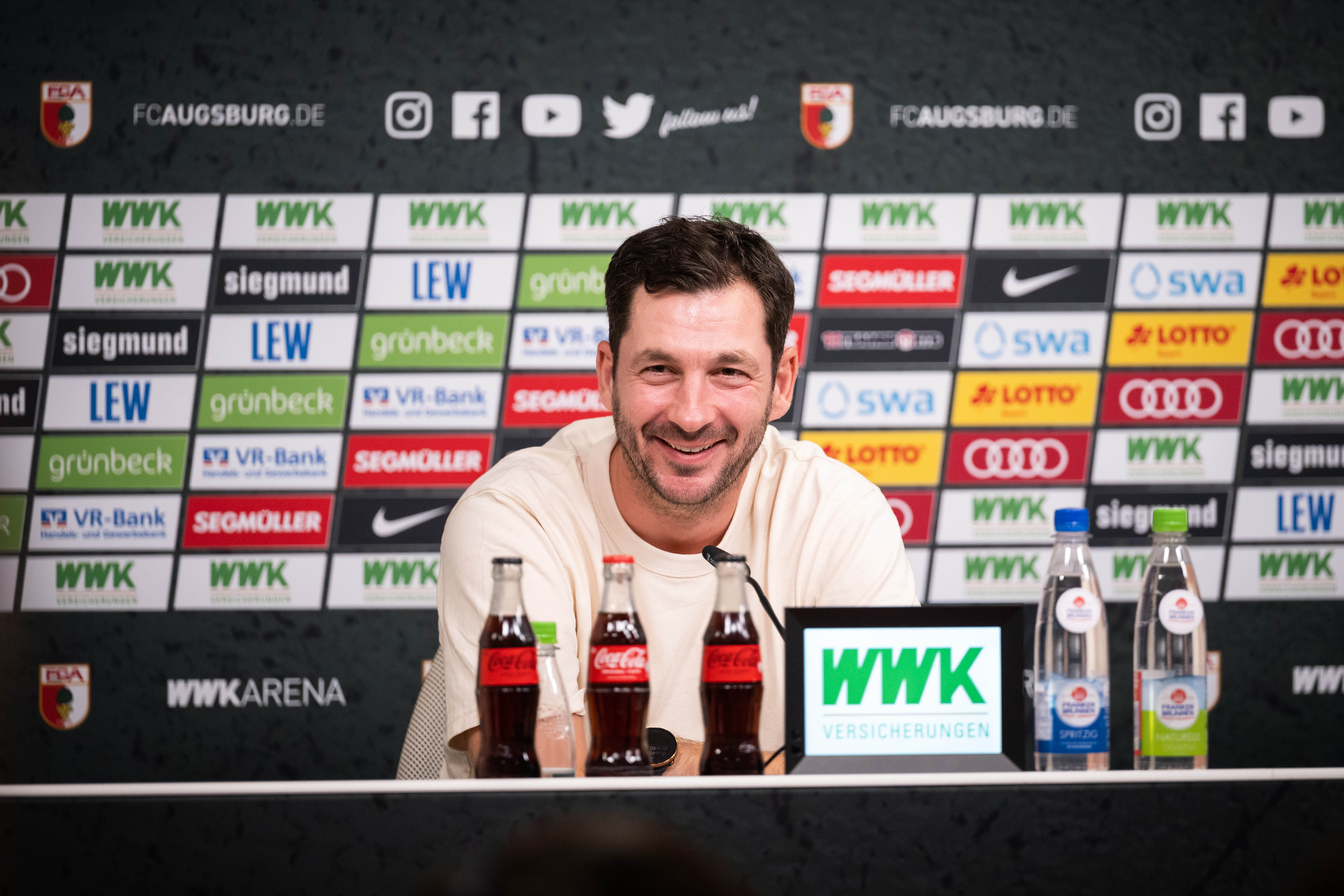 Sandro Schwarz lacht auf der Pressekonferenz nach dem Sieg in Augsburg.