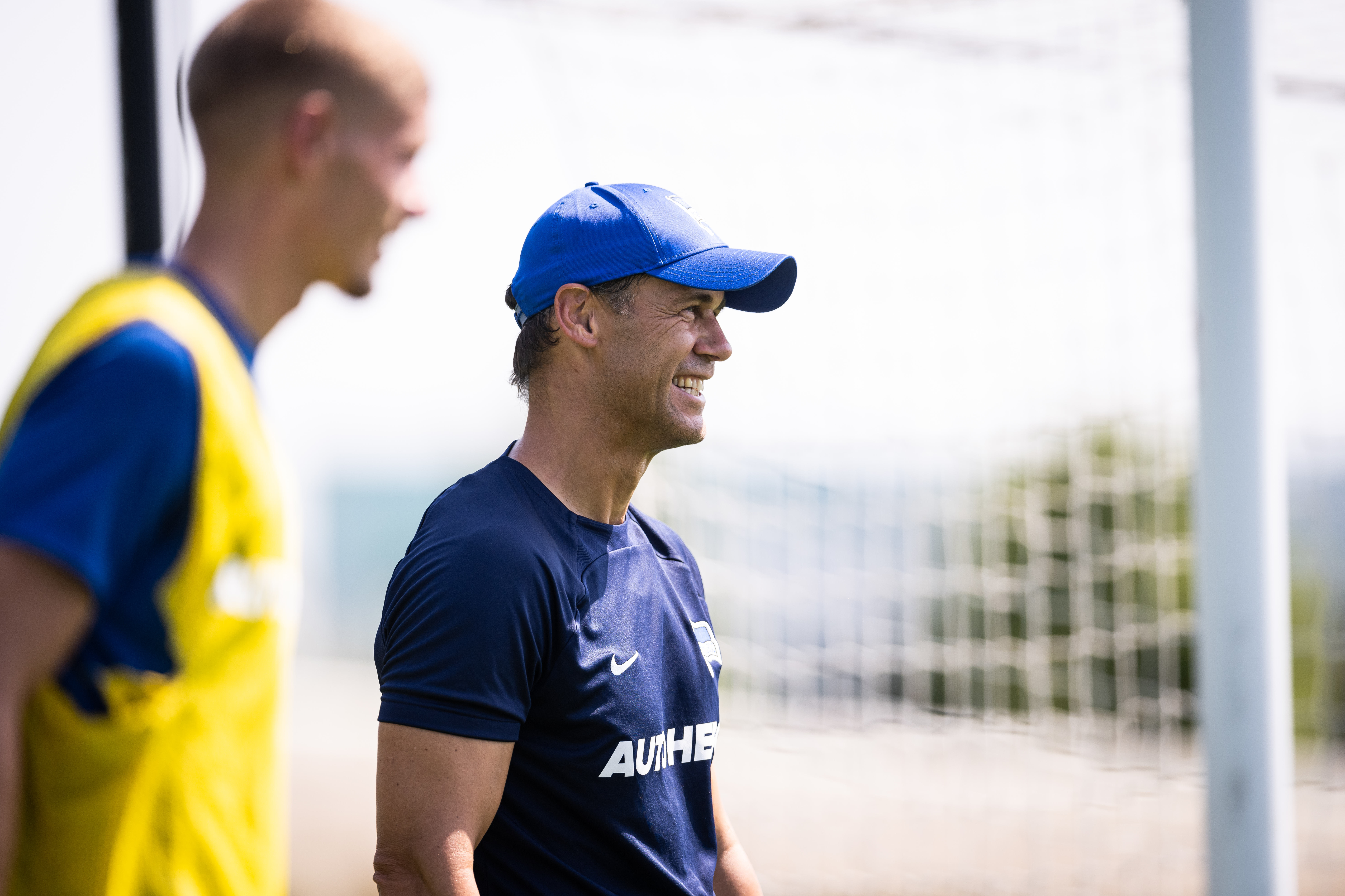 Tamás Bódog im Profil während er auf dem Trainingsplatz lacht.