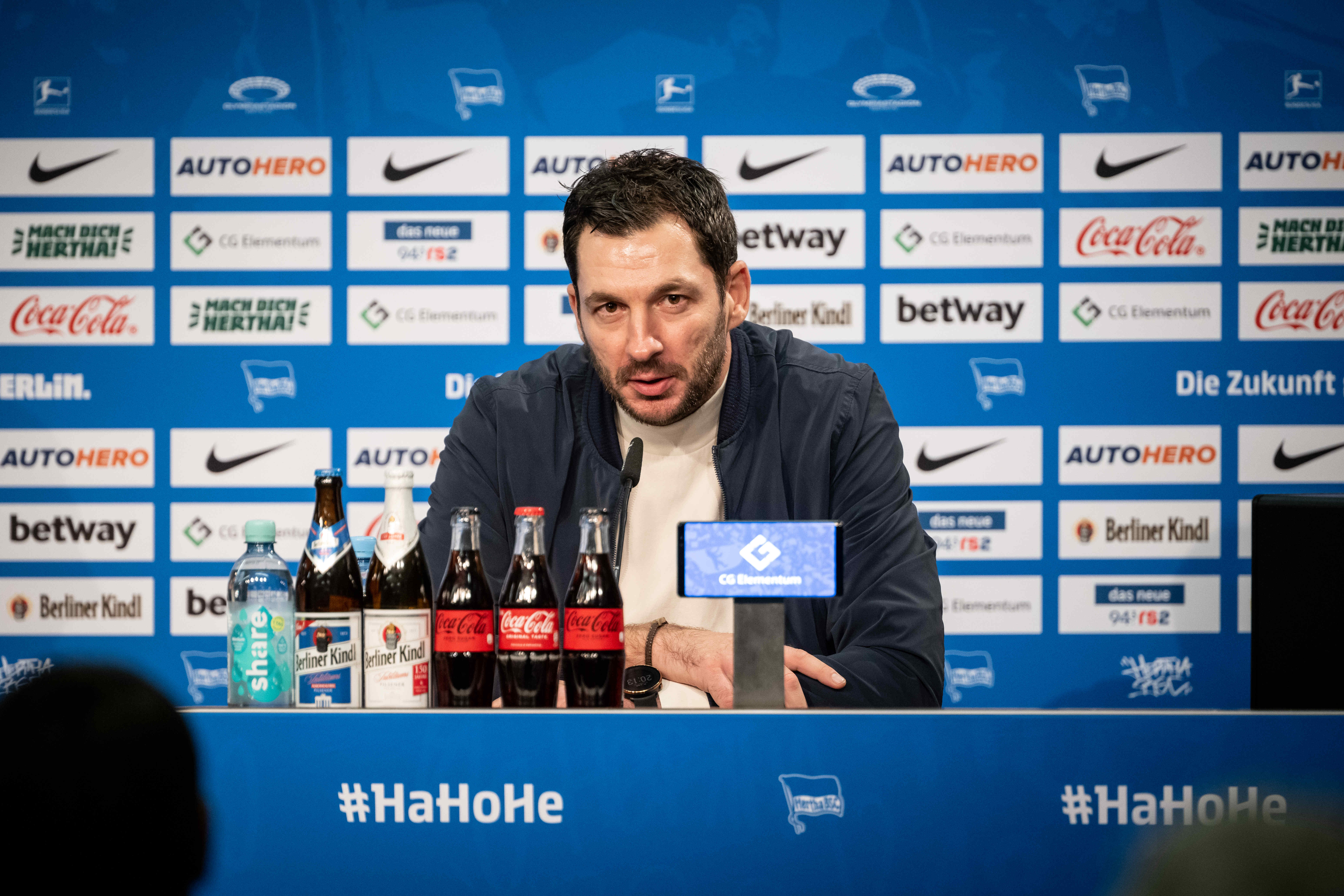 Sandro Schwarz sitzt auf dem Podium bei der Pressekonferenz.