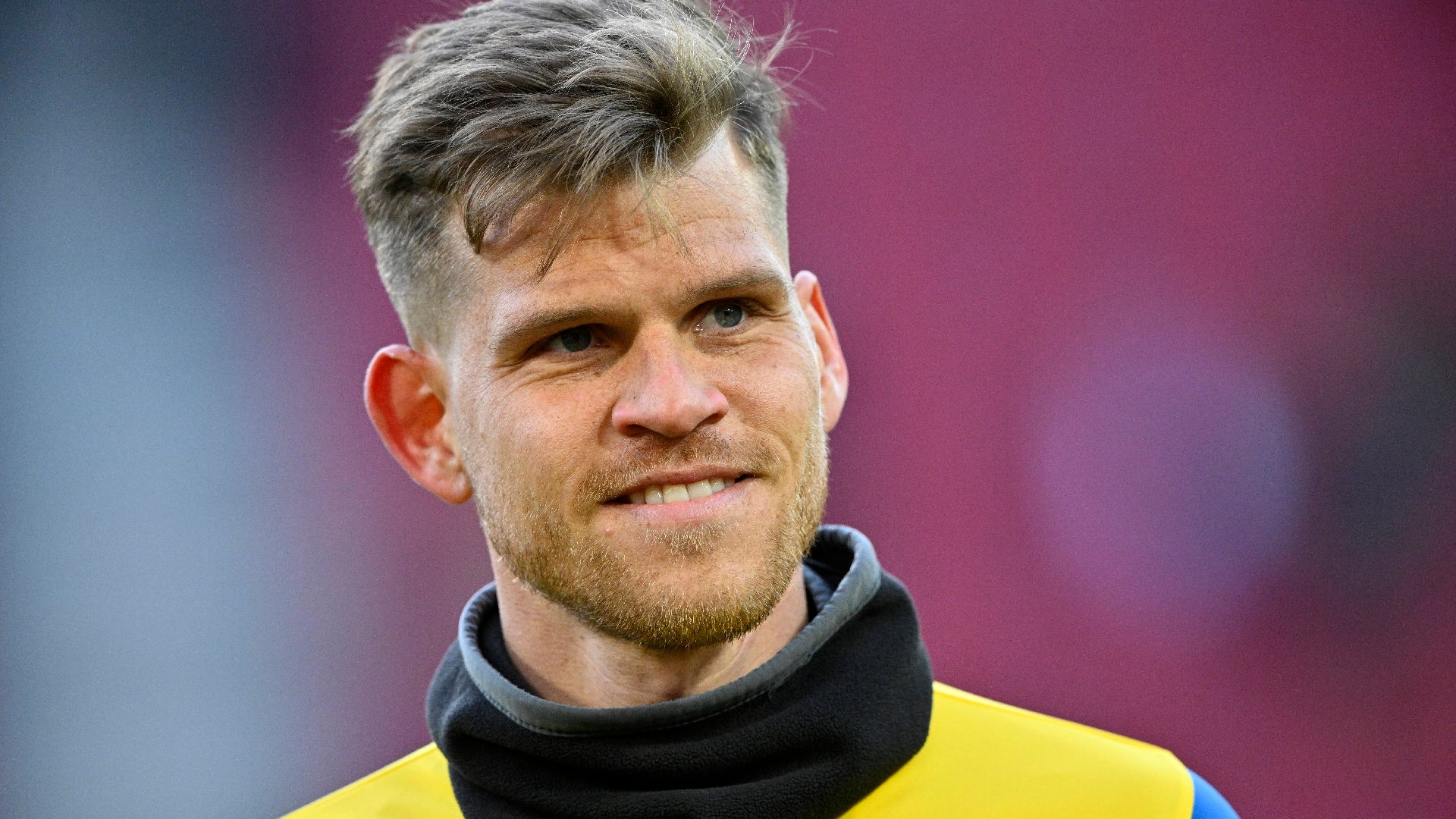 Florian Niederlechner lächelt beim Aufwärmen auf dem Platz.