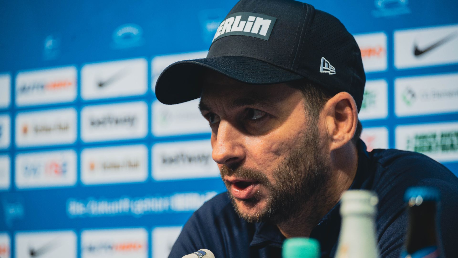 Sandro Schwarz sitzt auf dem Podium im PK-Raum.