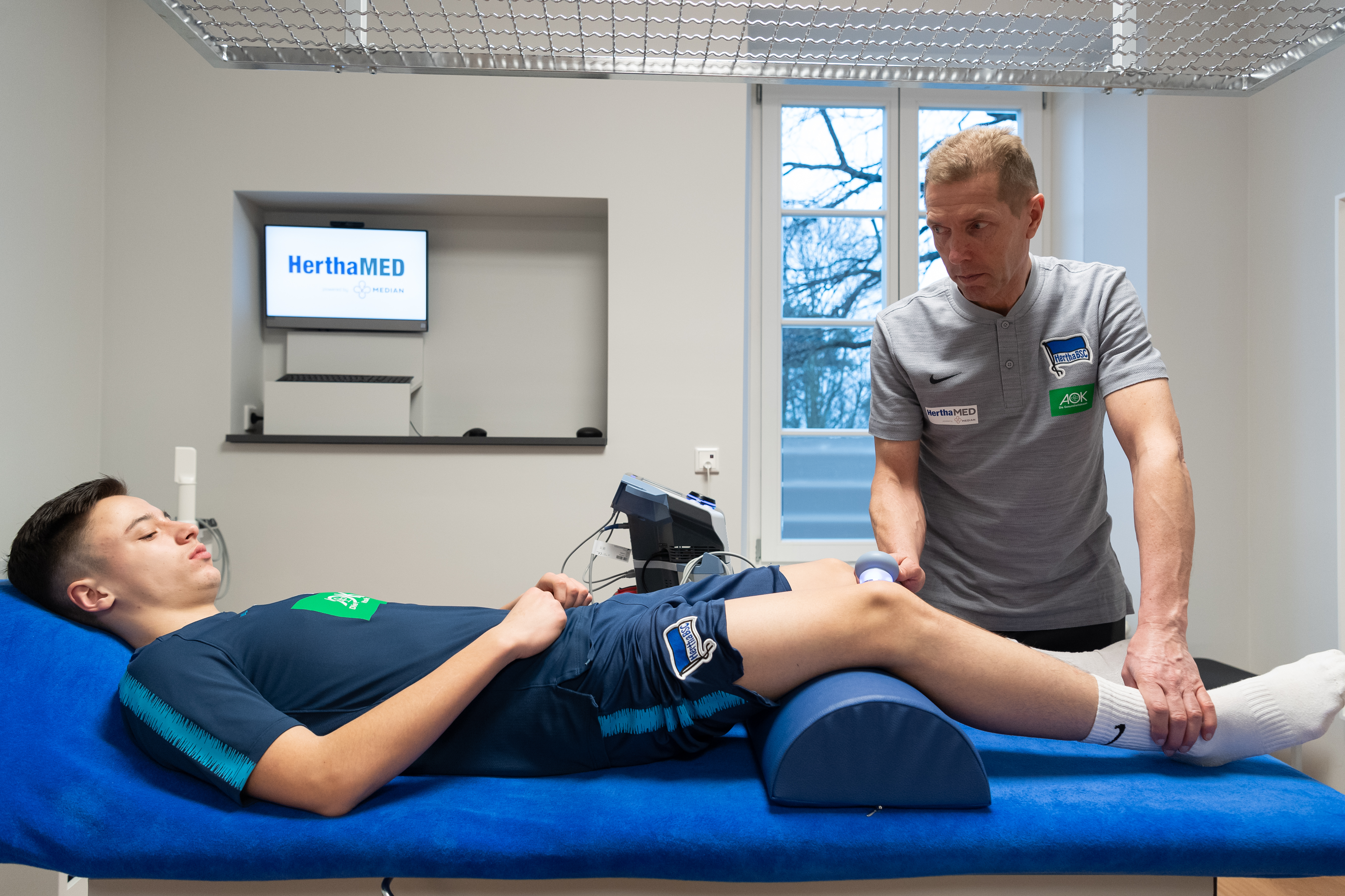 Leiter Jürgen Lange behandelt einen verletzten Akademie-Spieler im HerthaMED.