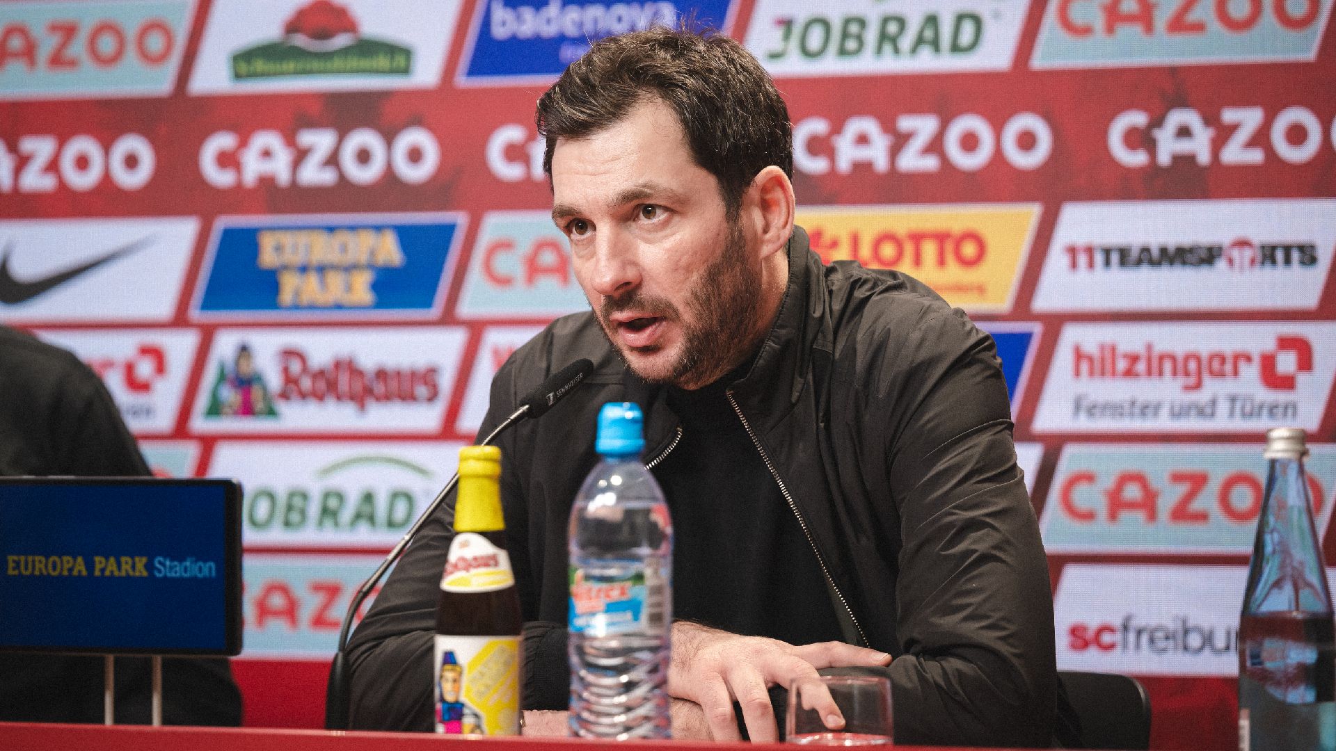 Sandro Schwarz spricht bei einer Pressekonferenz ins Mikrofon.