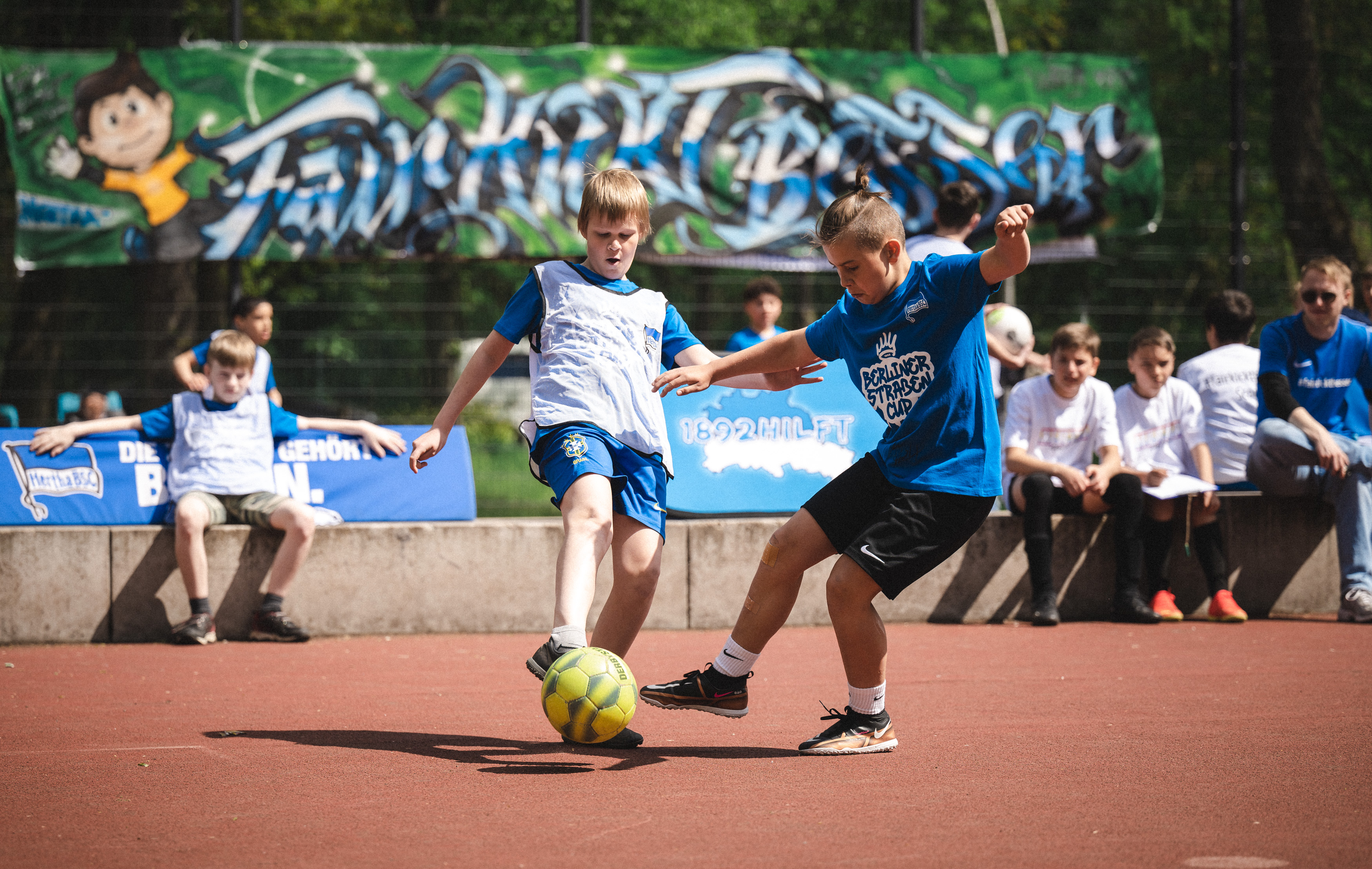 Zwei Teilnehmer des Berliner Straßen Cups 2023 kämpfen im Käfig um den Ball.