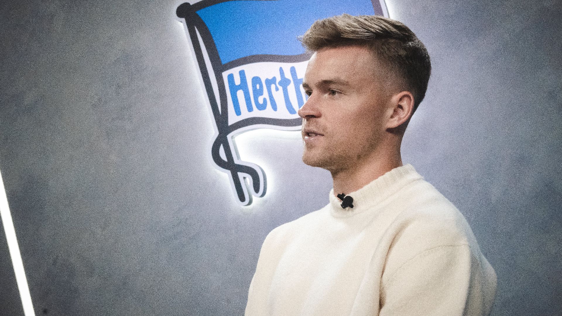 Maximilian Mittelstädt sitzt vor der Hertha-Fahne in unserer Traumfabrik.