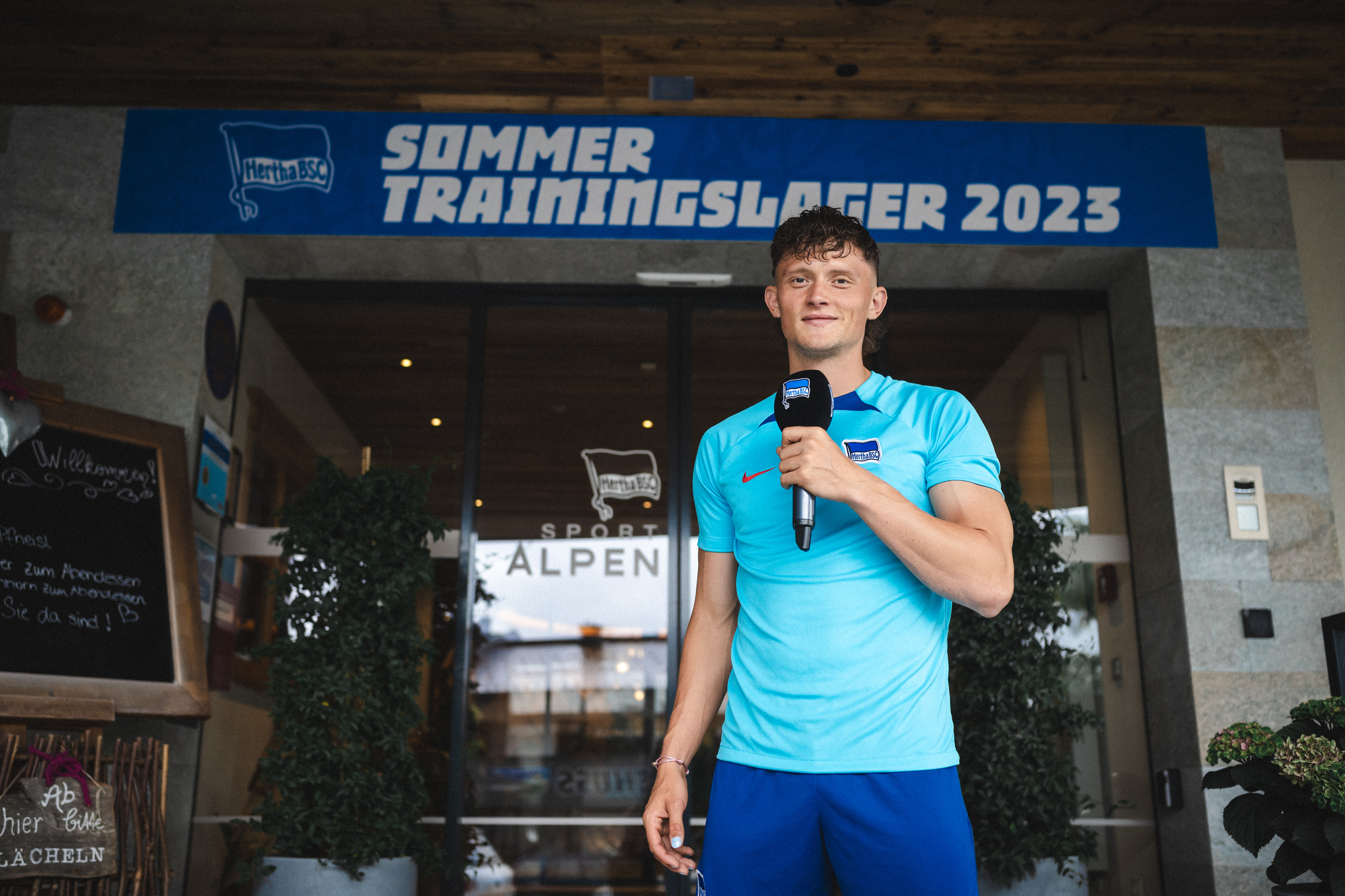 Fabian Reese steht mit einem Mikro in der Hand vor dem Hotel in Zell am See.