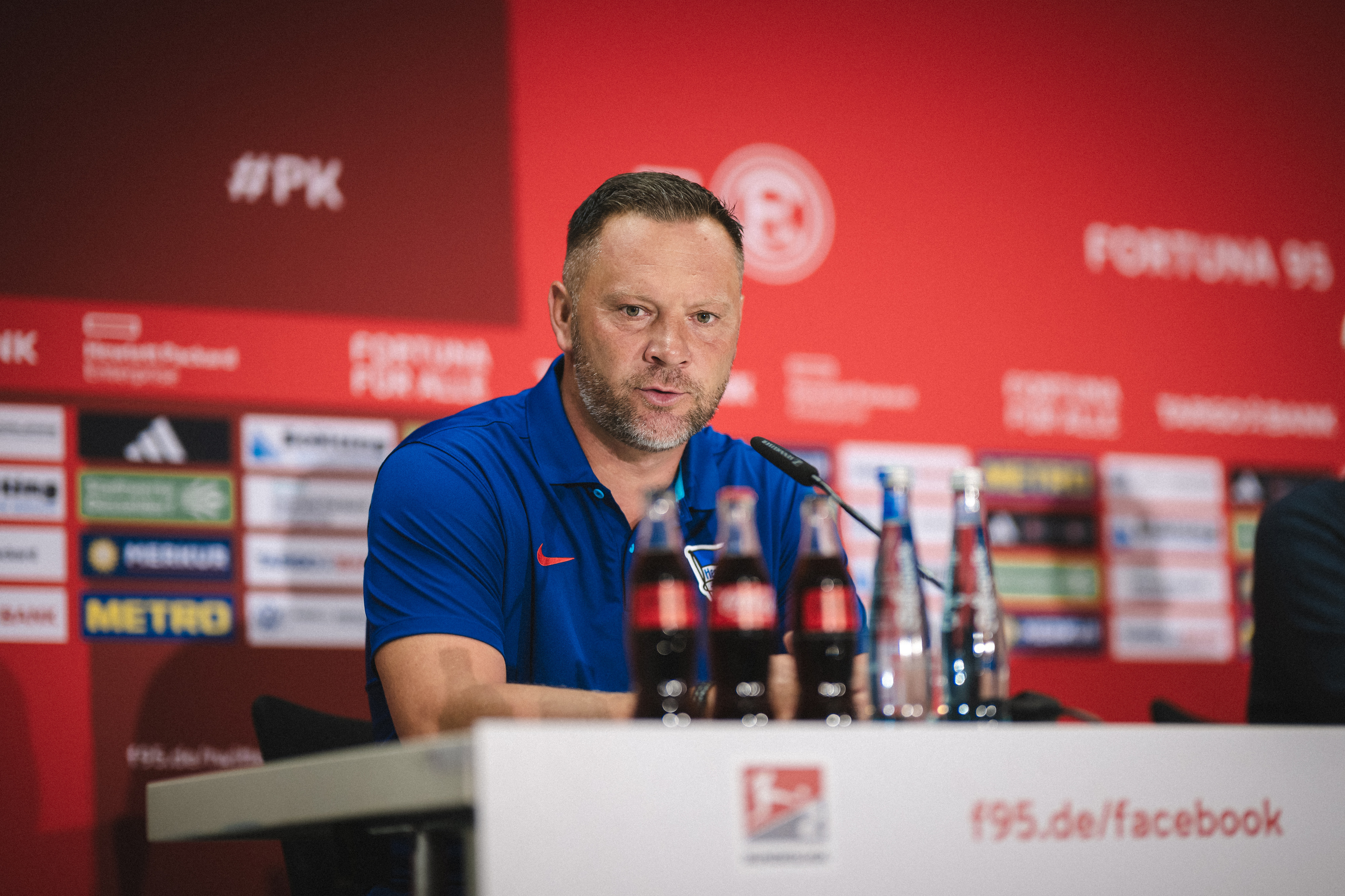 Pál Dárdai sitzt bei der Pressekonferenz auf dem Podium und spricht.