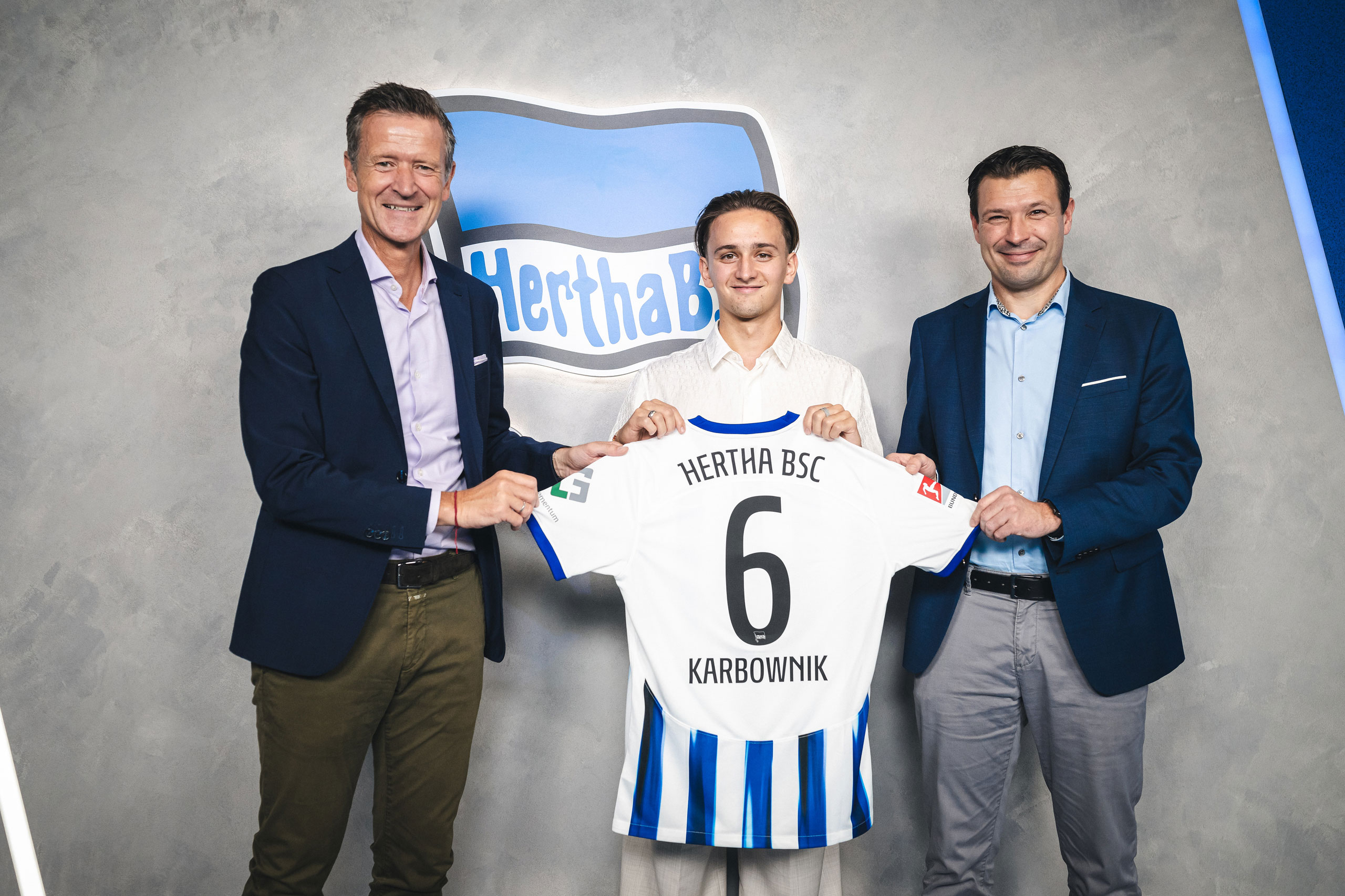 Thomas E. Herrich, Michał Karbownik and Benjamin Weber hold up a Hertha shirt.