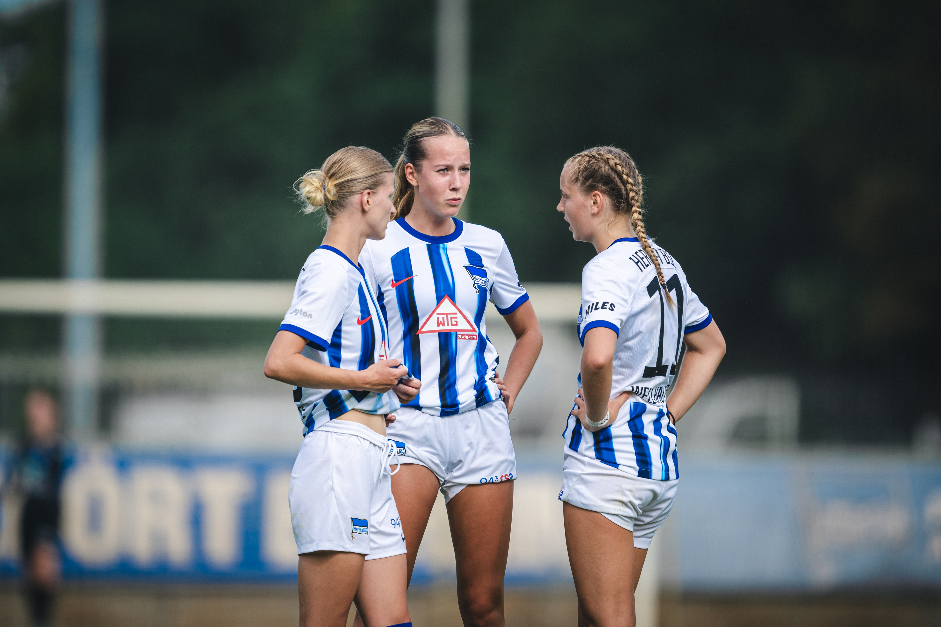 Lilli Genthe, Svenja Poock und Elfie Wellhausen im Gespräch auf dem Rasen.