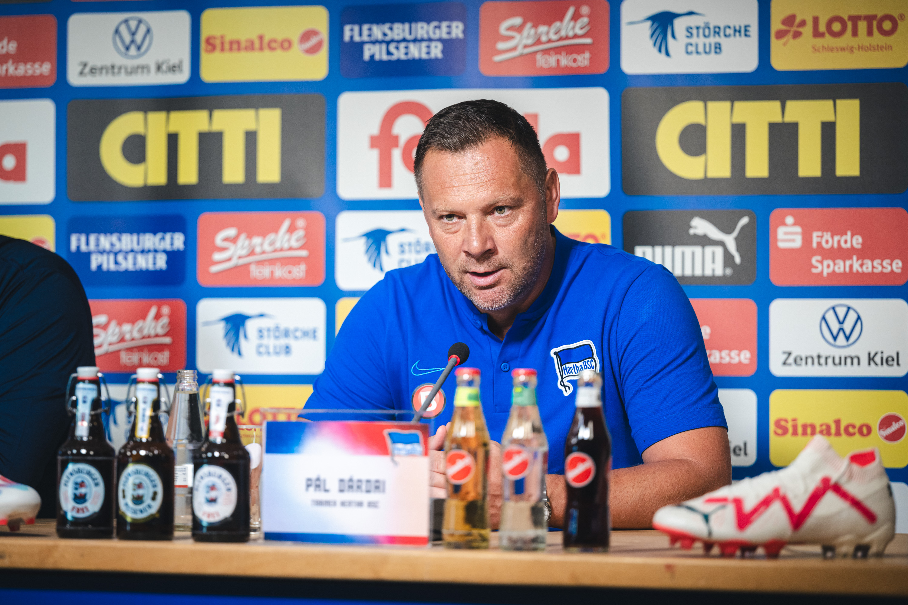 Pál Dárdai sitzt auf dem Podium vor dem Mikrofon.