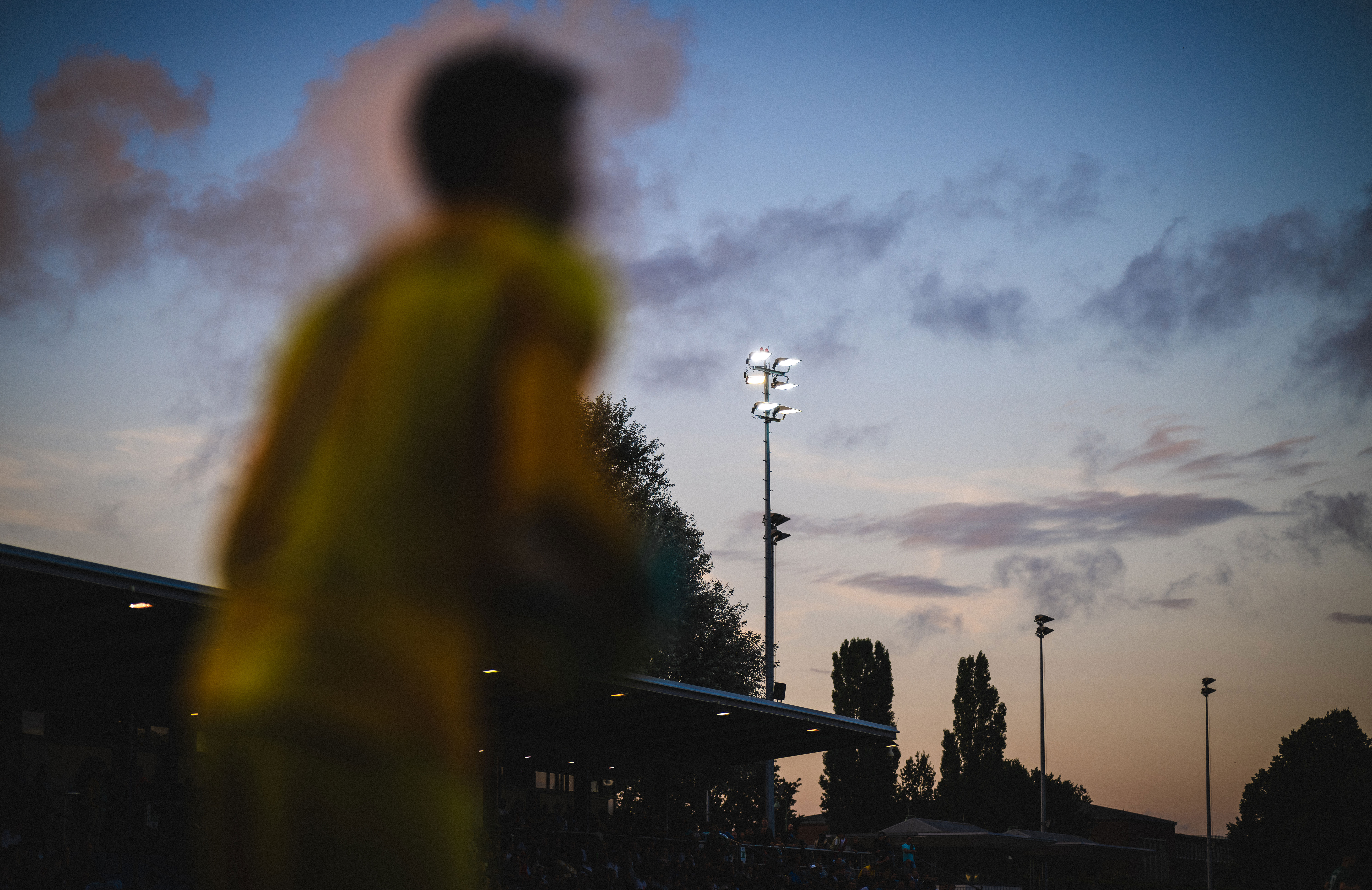 Blick ins Stadion auf dem Wurfplatz/Amateurstadion unter Flutlicht in der Abenddämmerung.