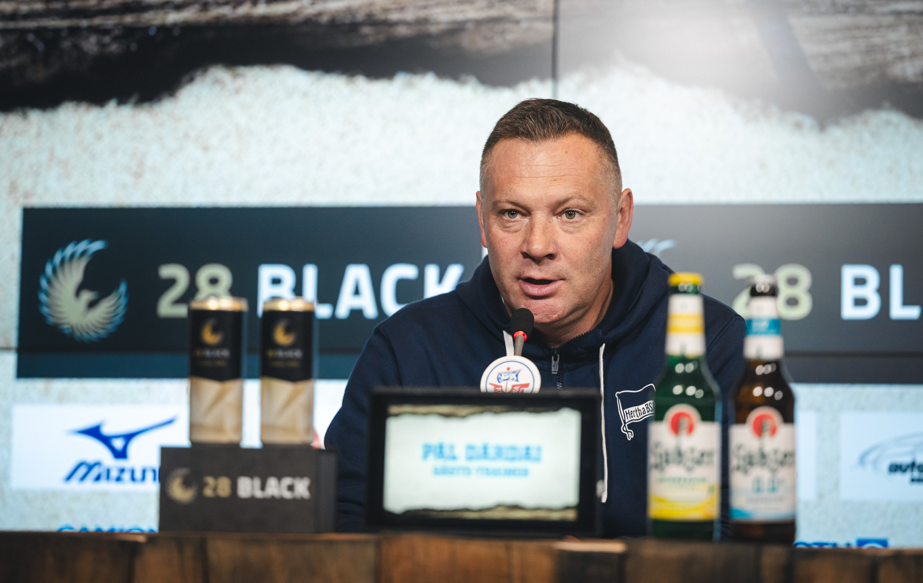 Pál Dárdai sitzt auf dem Podium hinter dem Mikro.