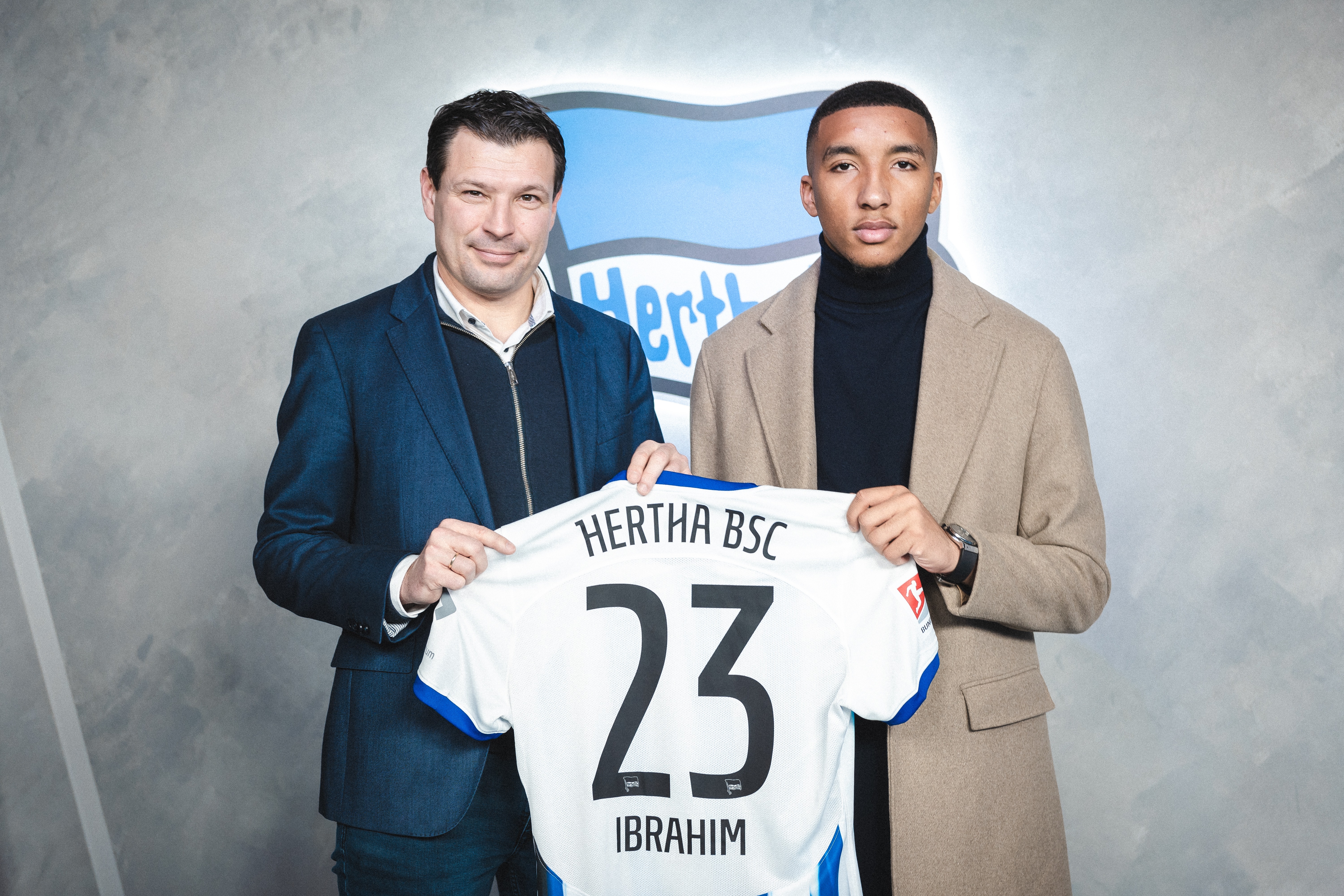 Bradley Ibrahim und Benjamin Weber halten das blau-weiße Trikot mit der Nummer 23 hoch.