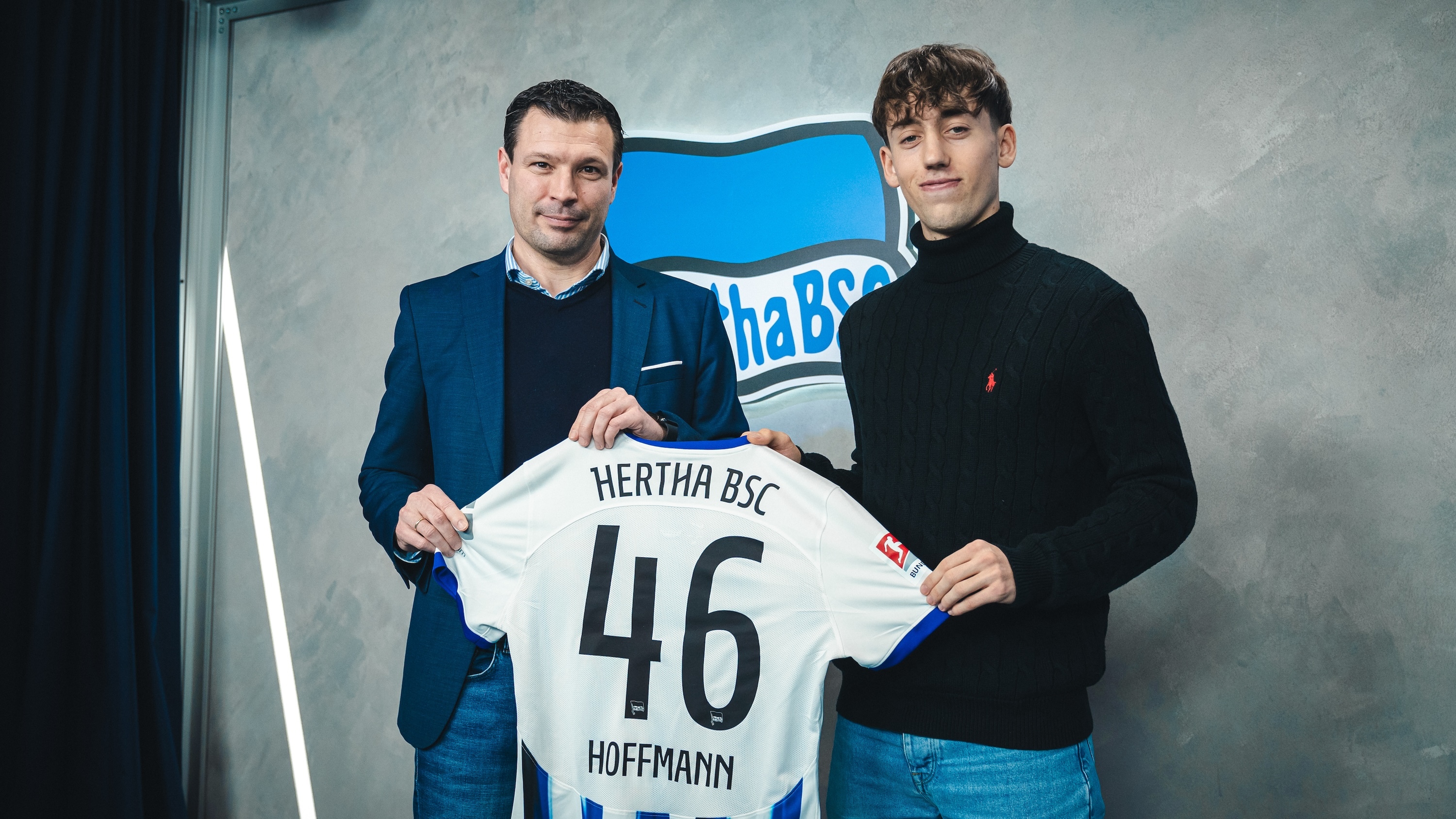 Tim Hoffmann hält gemeinsam mit Sportdirektor Benjamin Weber sein Hertha-Trikot in die Kamera.