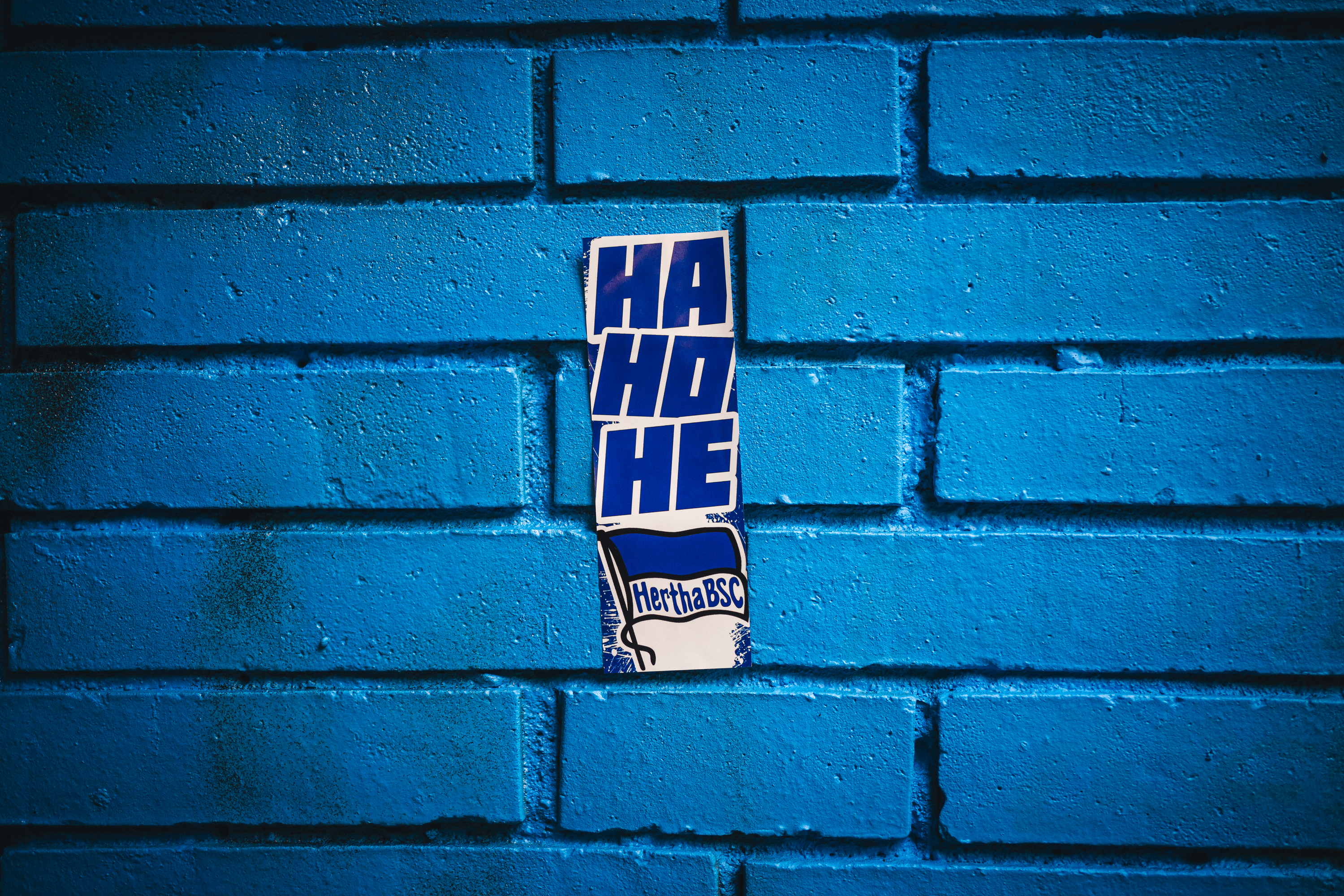 Ein Hertha-Sticker auf einer blauen Wand.