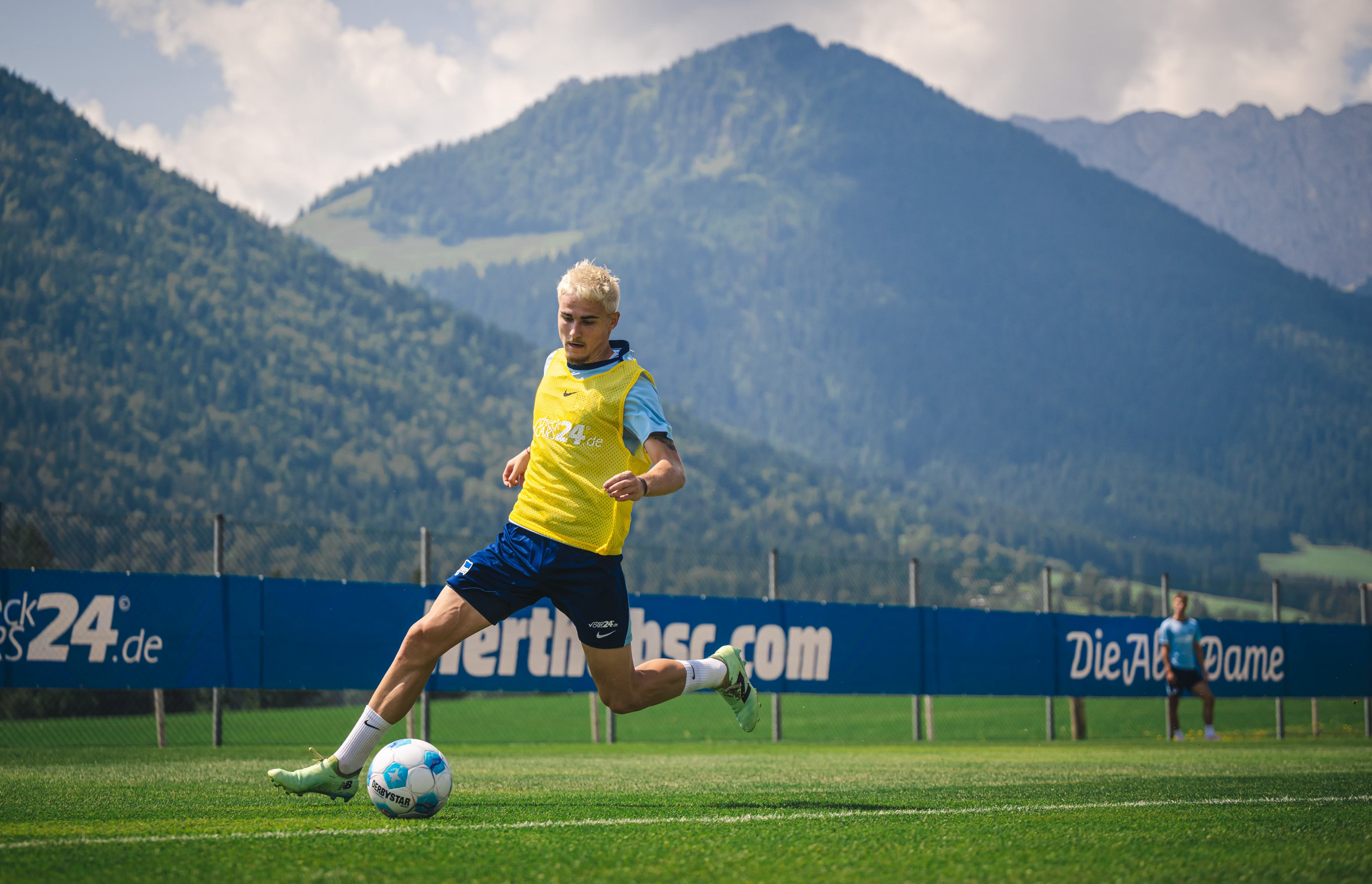 Marten Winkler treibt vor einem Bergpanoram den Ball nach vorne.