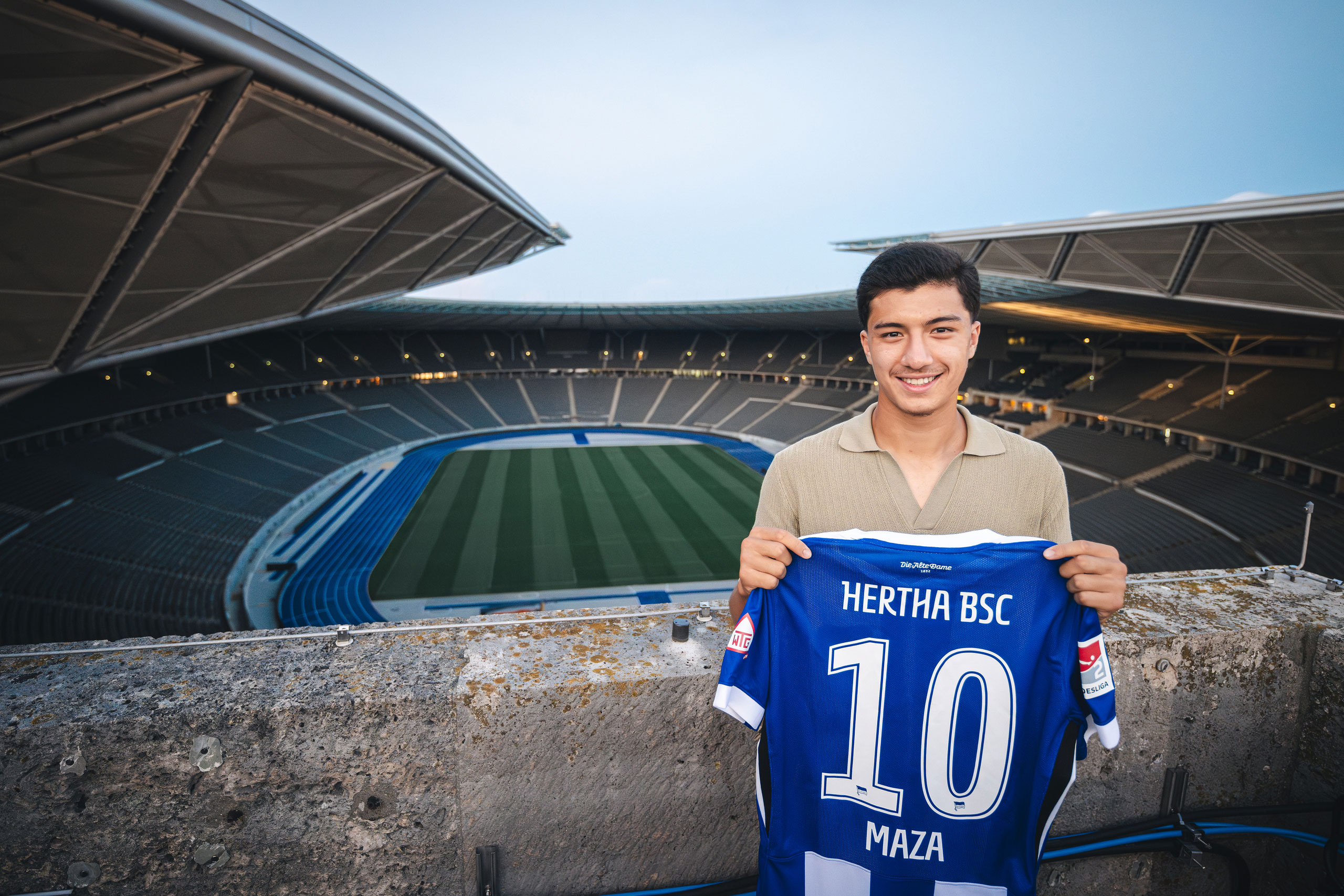 Ibrahim Maza steht auf einem Turm am Olympiastadion und zeigt sein Trikot.