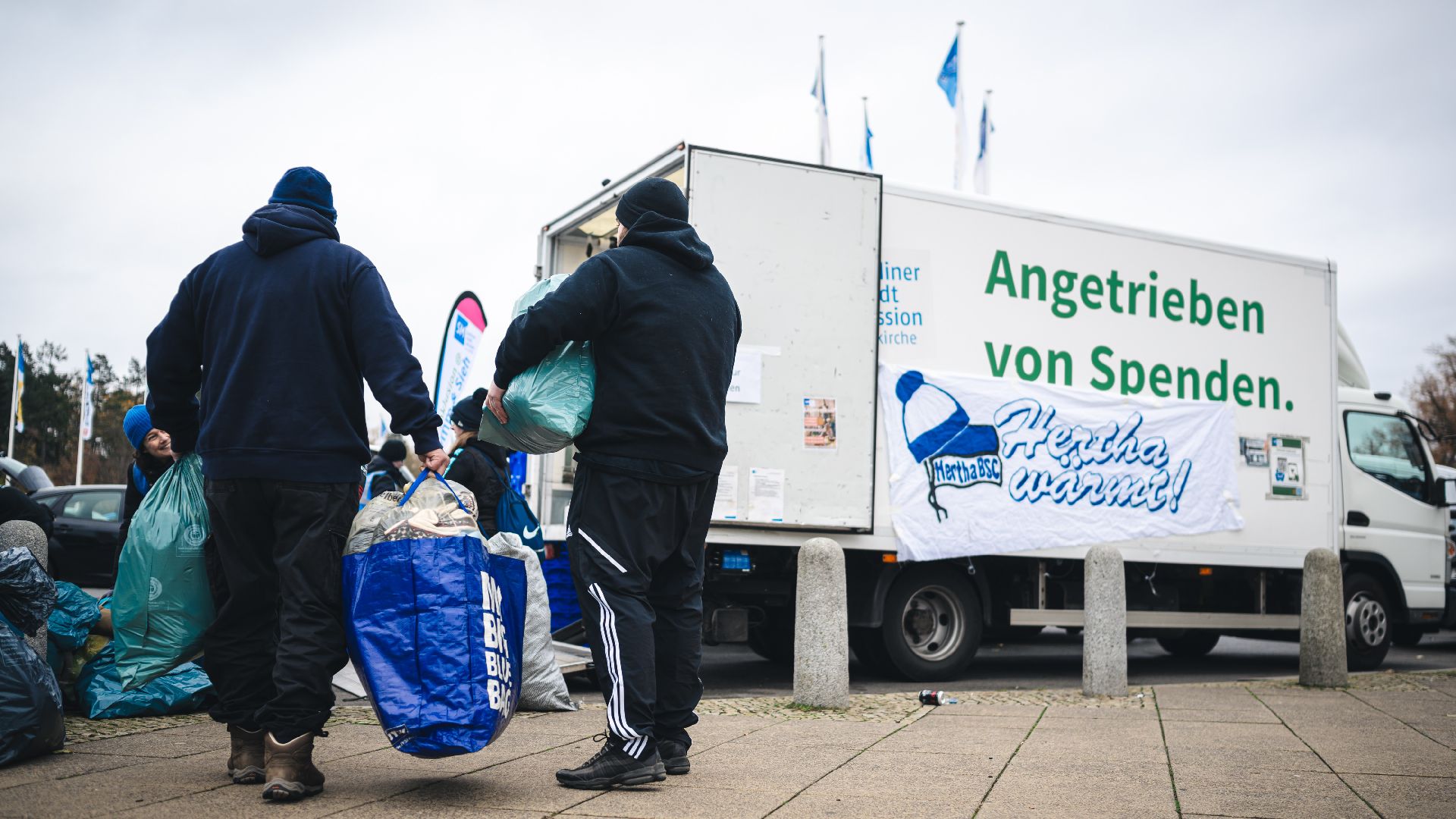 Helfer verstauen Kleidung rund um 'Hertha wärmt'.