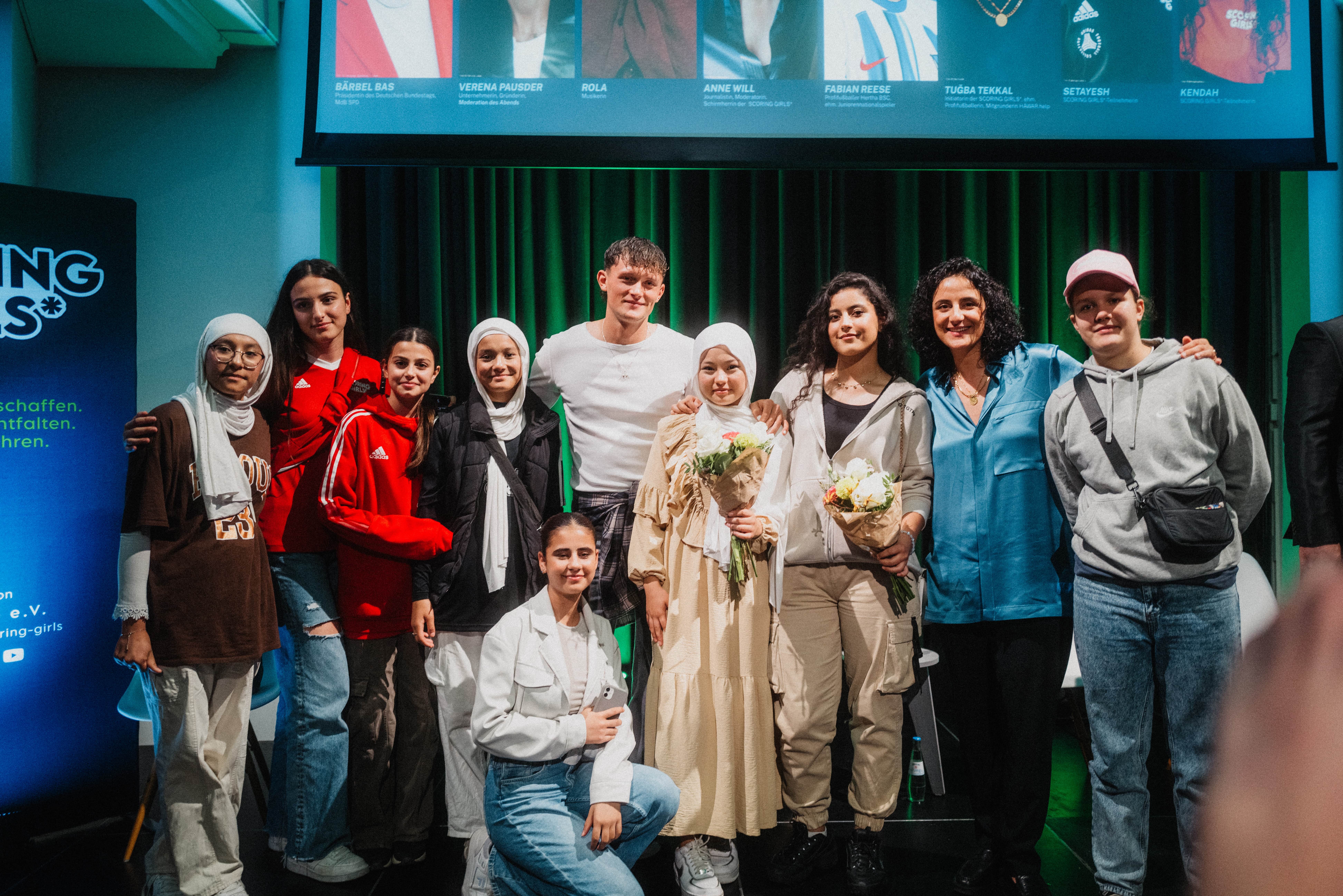 Fabian Resse und Tuğba Tekkal posieren mit einigen SCORING GIRLS* zum Gruppenfoto.
