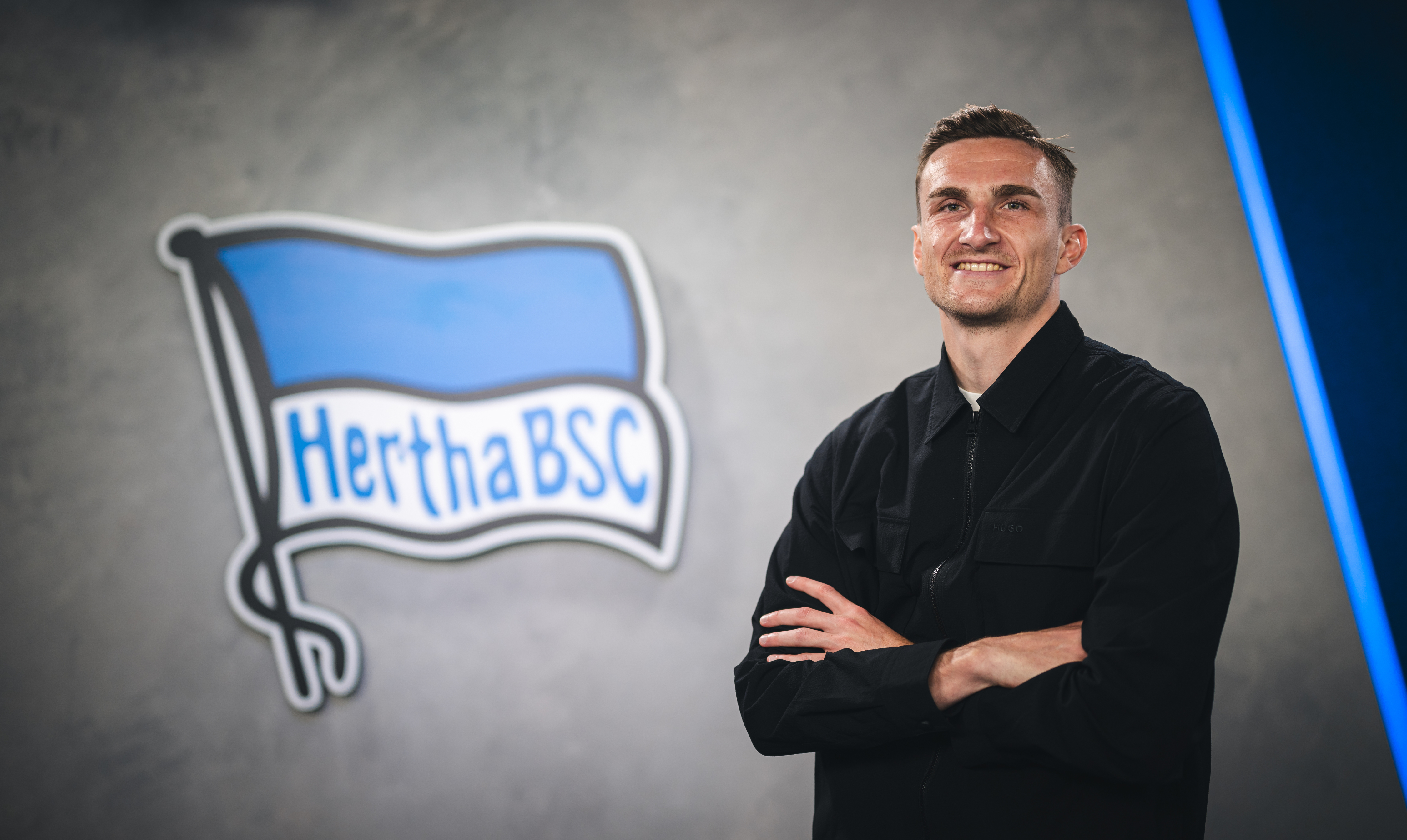 Niklas Kolbe posiert vor der Fahne.