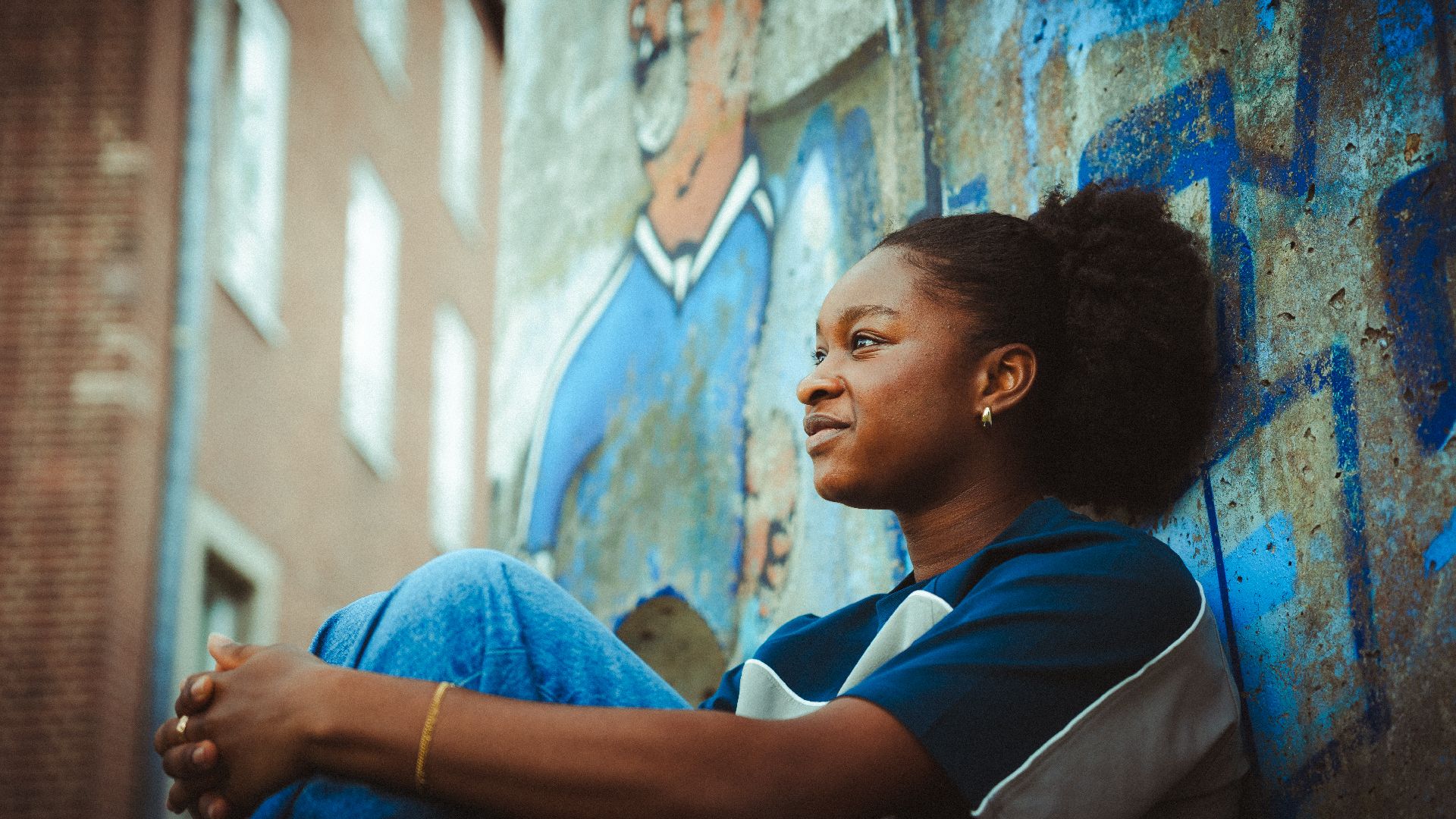 Mona Sarr lehnt an der Berliner Mauer.