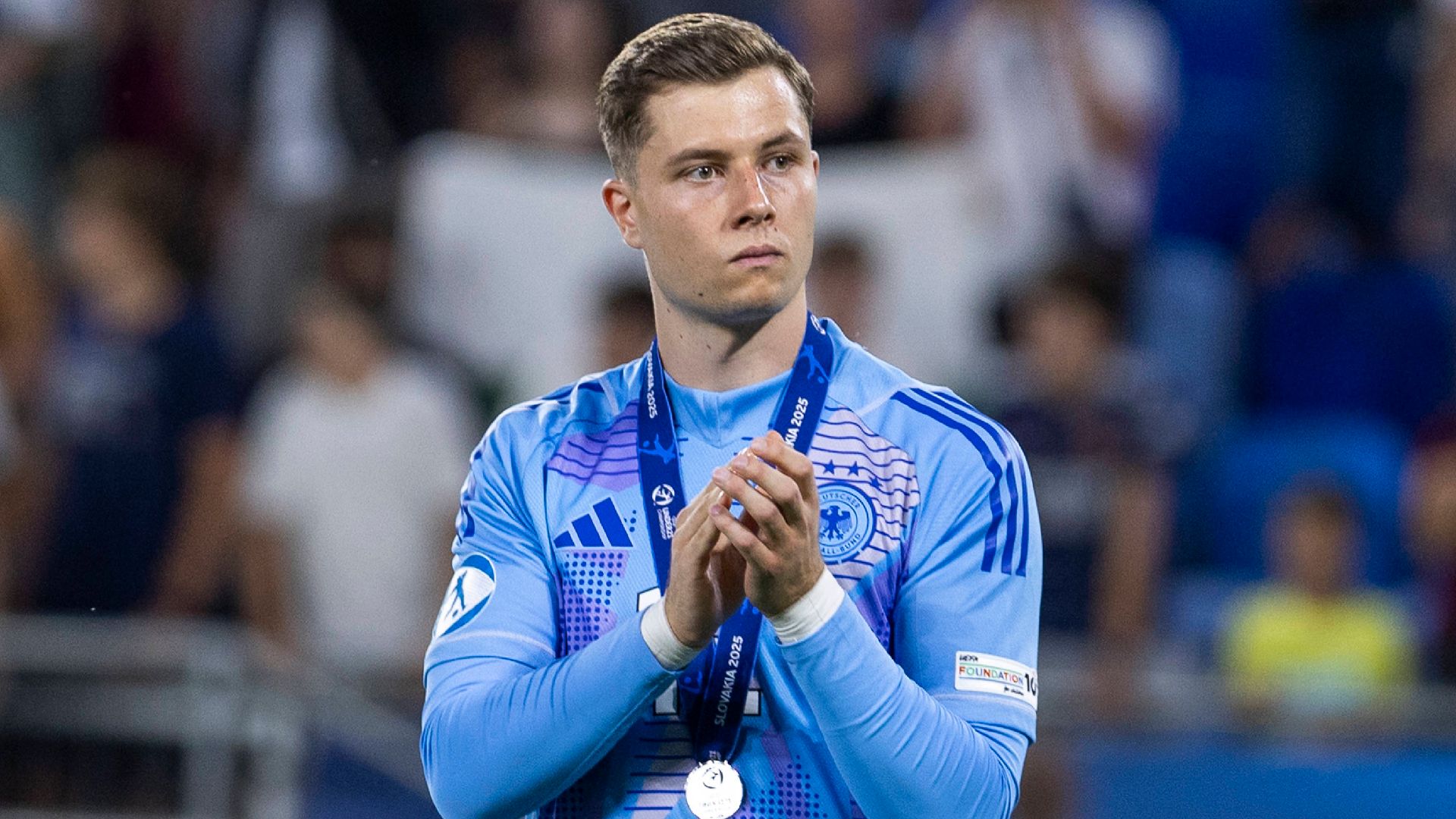 Tjark Ernst applaudiert mit leerem Blick und Silbermedaille um den Hals.