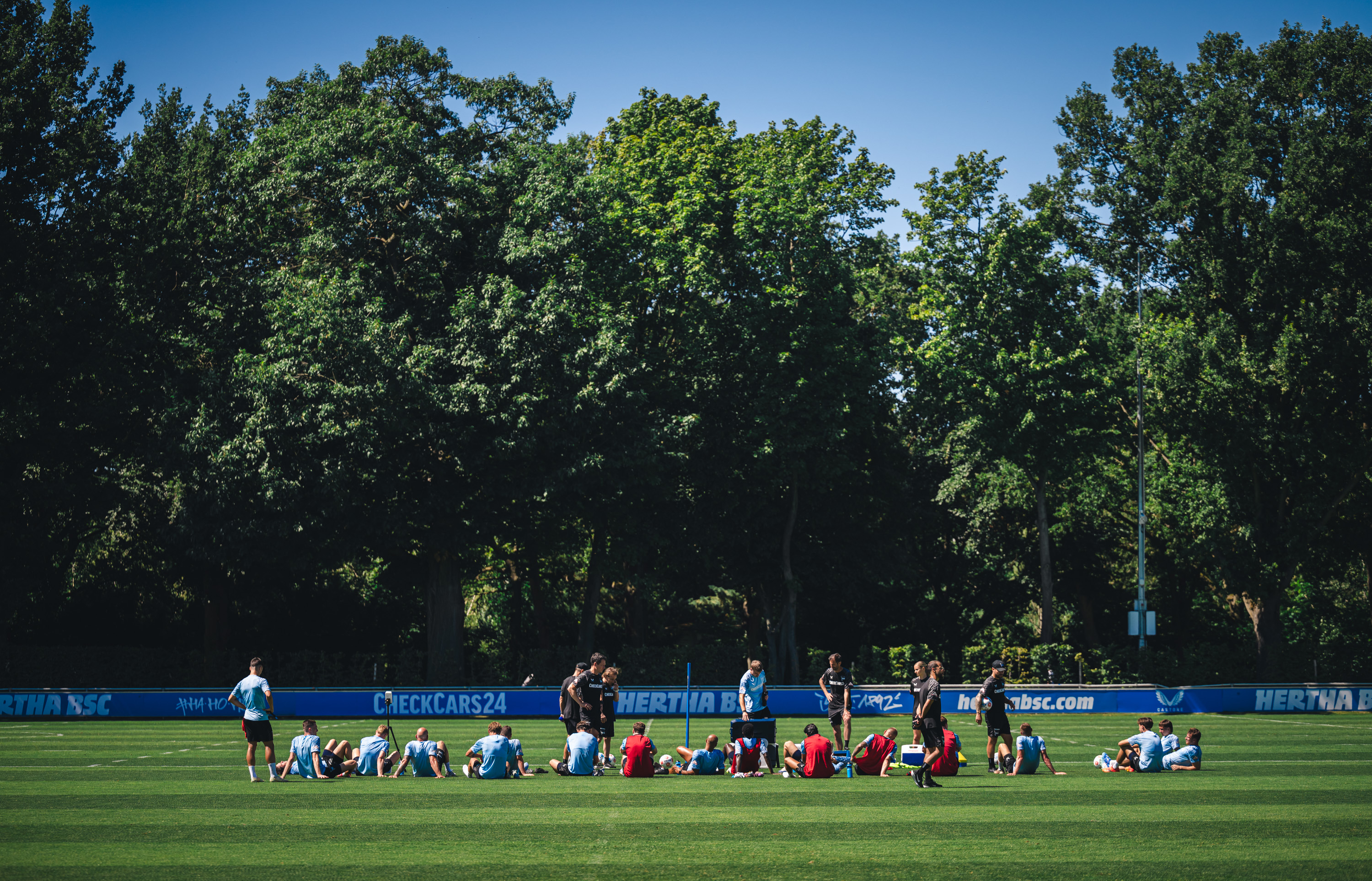 Die Mannschaft sitzt nach dem Training auf dem Rasen.