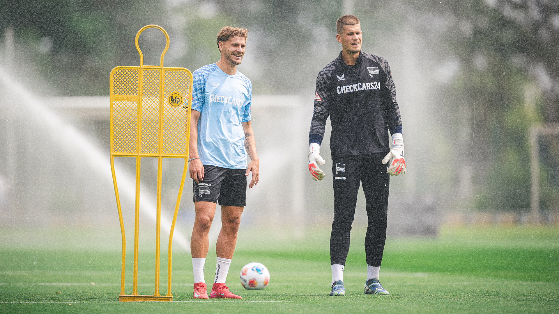 Pascal Klemens und Dennis Smarsch stehen mit der neuen Trainingskollektion auf dem Platz.