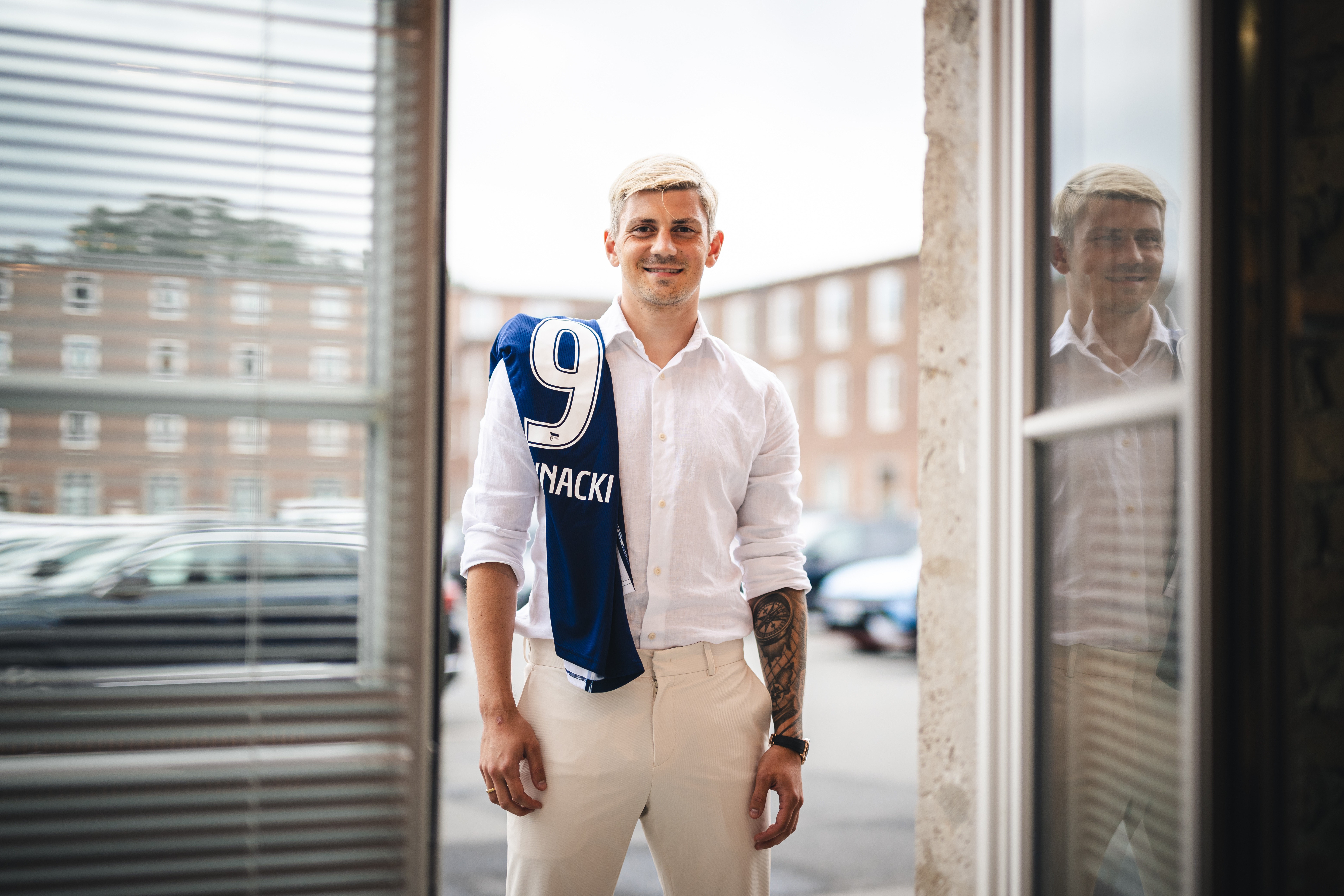 Dawid Kownacki steht mit einem Trikot über der Schulter am Fenster.