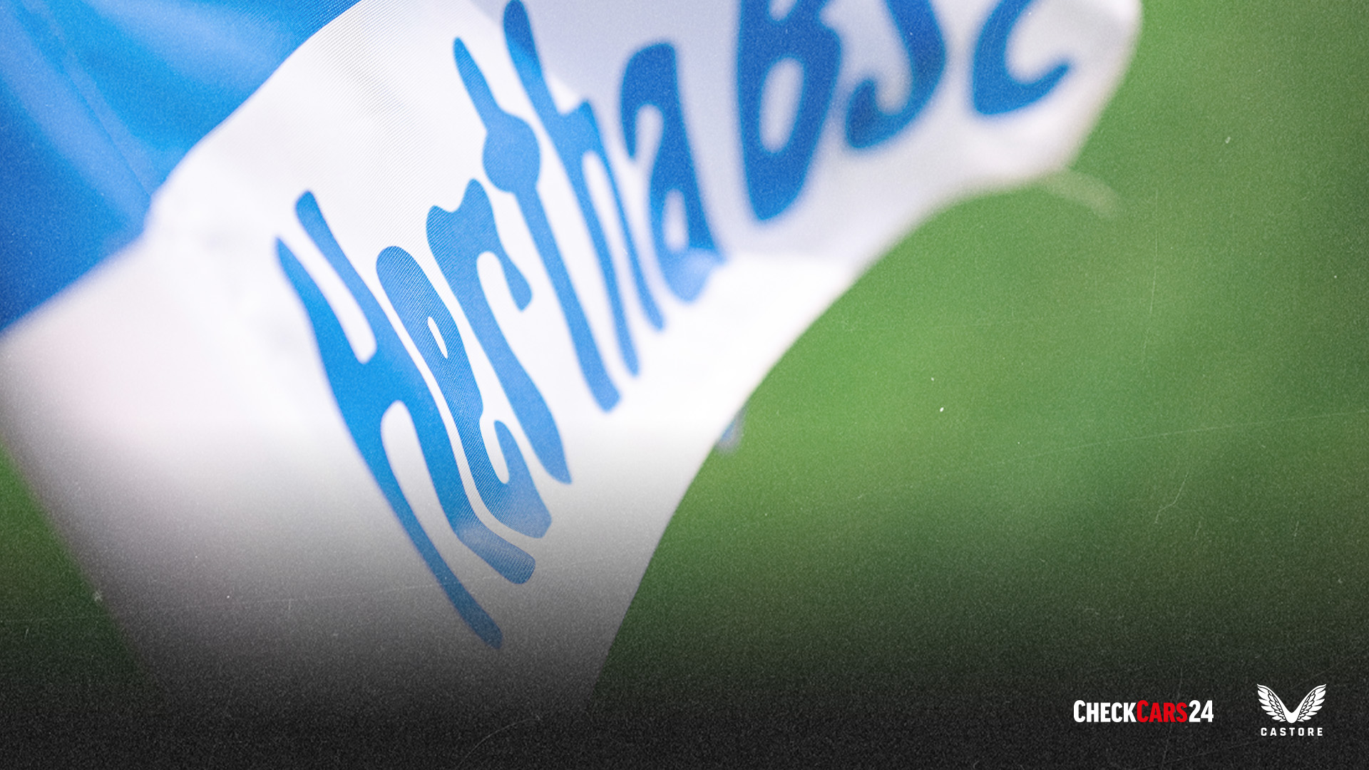 Im Hintergrund befindet sich die Hertha BSC-Fahne. Davor sind das Hertha-Logo und das Elversberg-Logo nebeneinander.