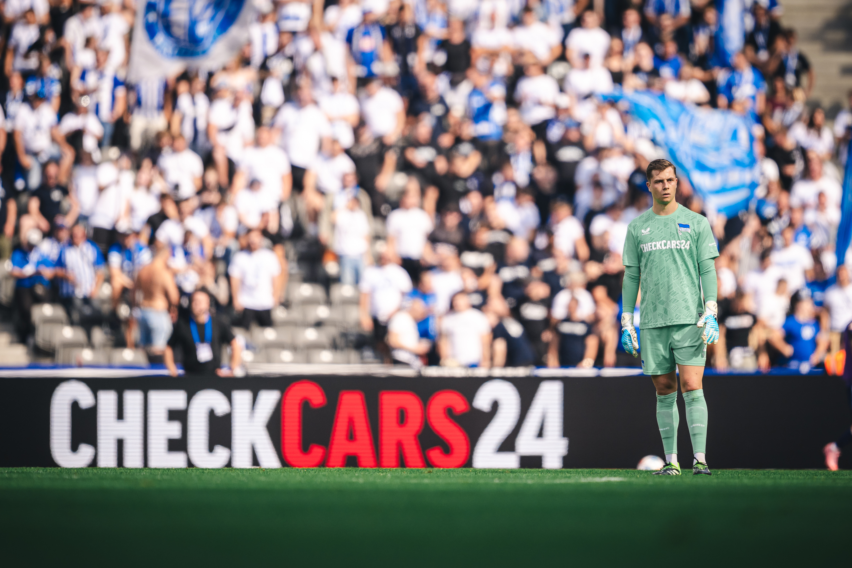 Tjark Ernst auf dem Platz mit den Fans im Hintergrund.