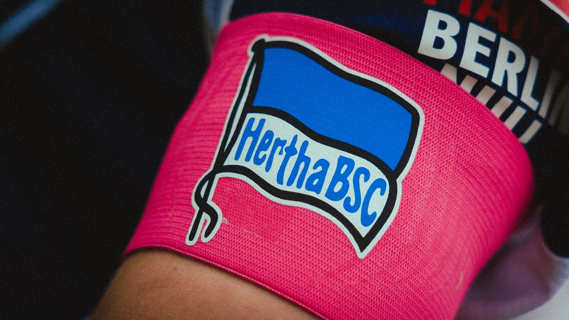 Eine pinke Kapitänsbinde mit der Hertha-Fahne.