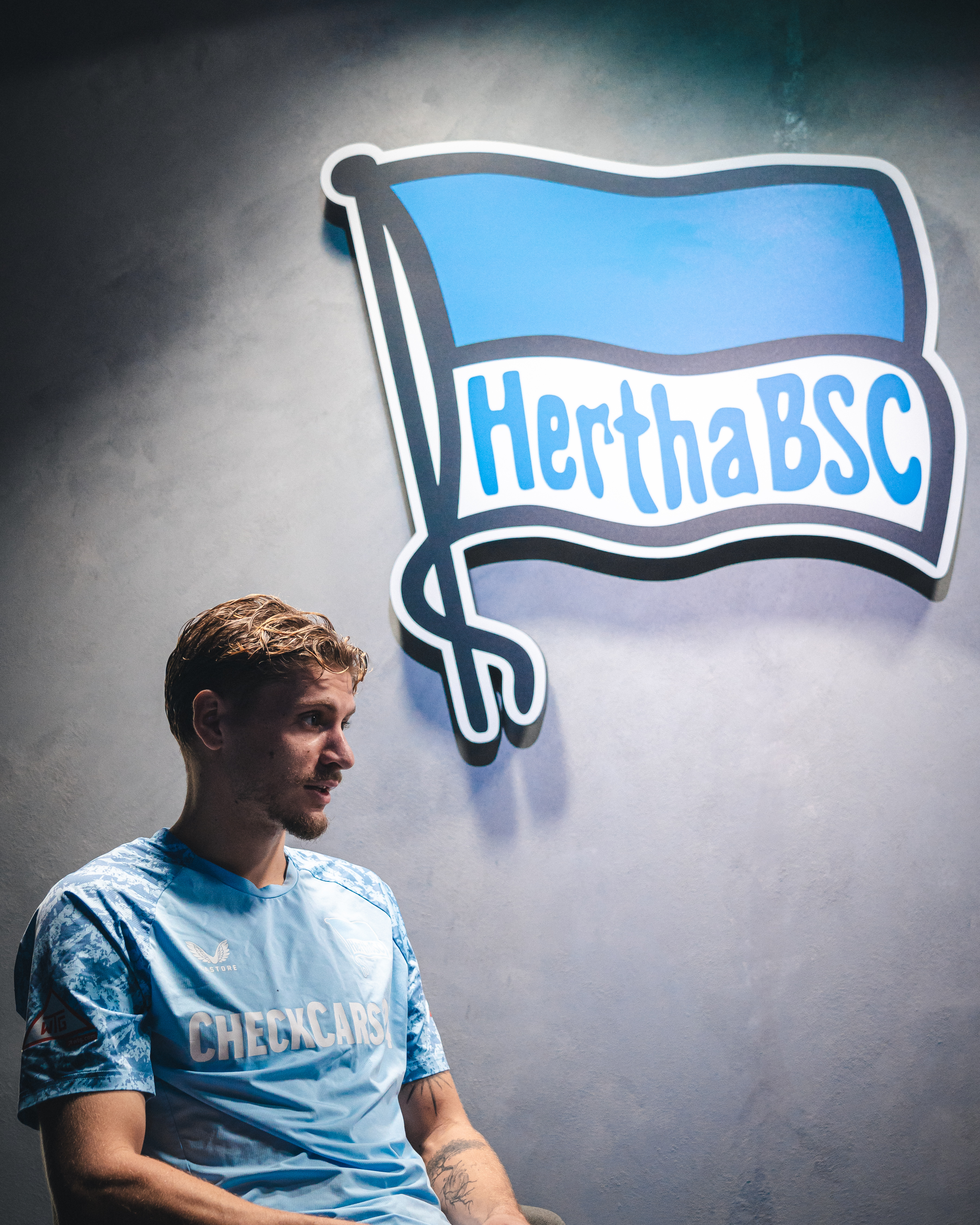 Márton Dárdai sitzt vor der Hertha-Fahne.