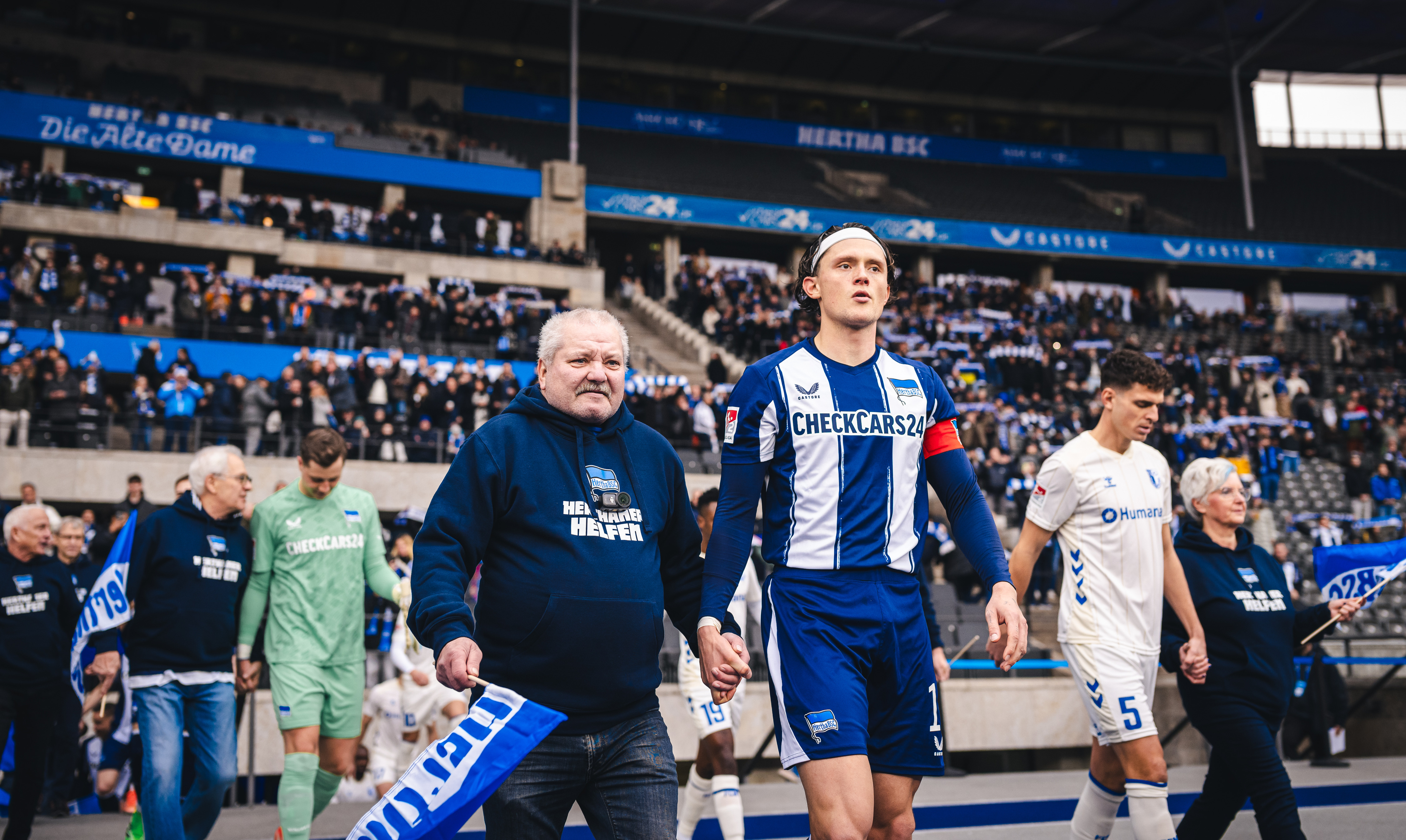 Fabian Reese läuft mit einem Ü60-Mitglied auf das Spielfeld ein.