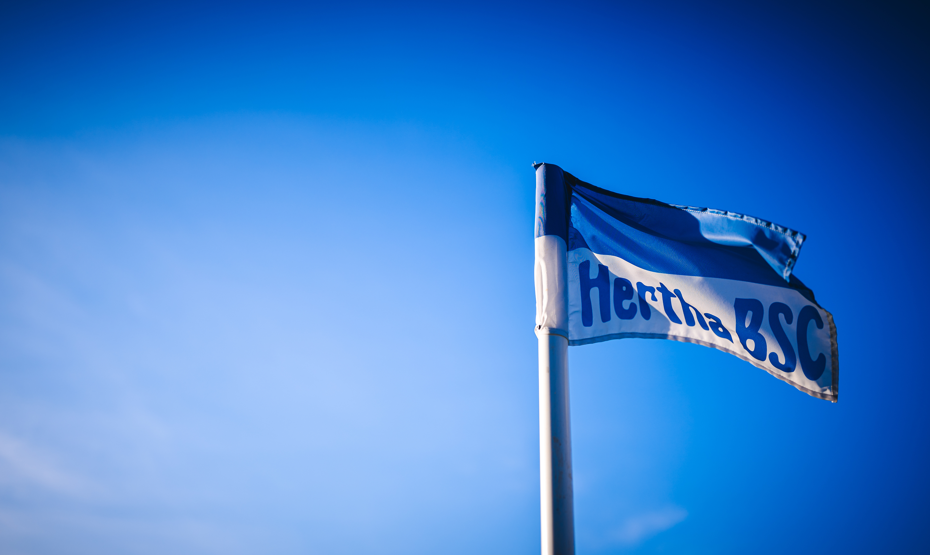 Eine Hertha-Fahne vor blauem Himmel.