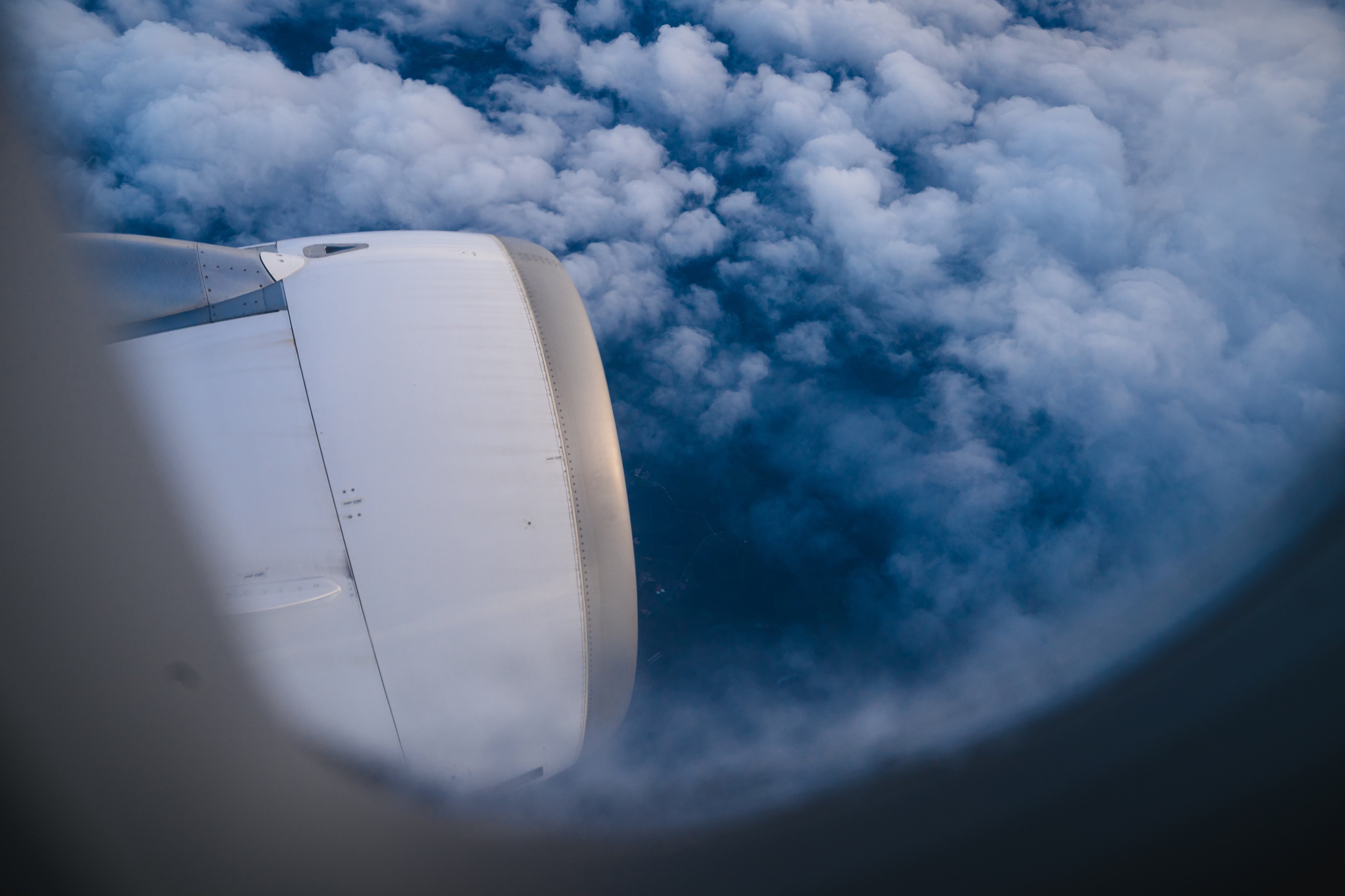 Der Blick aus einem Flugzeugfenster zeigt einen Propeller und Wolken.