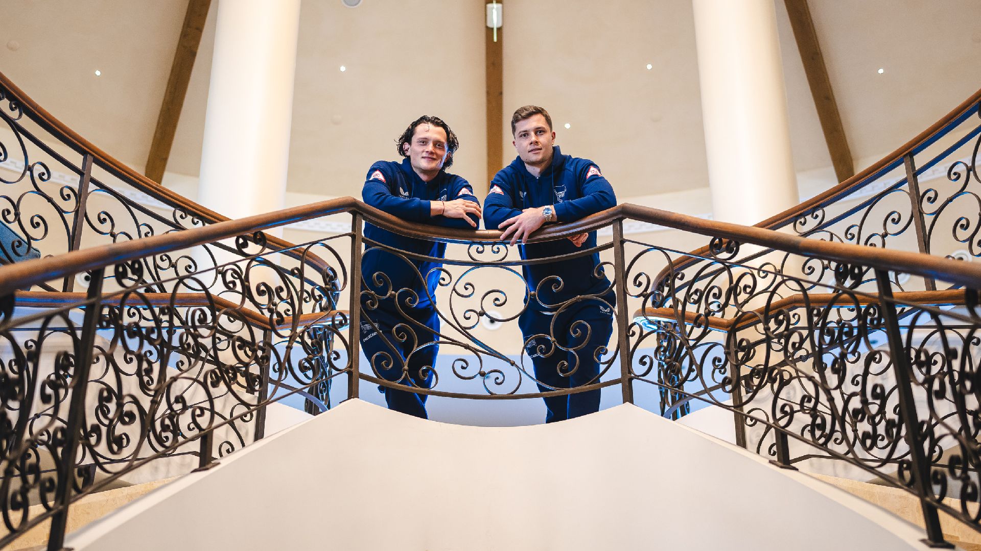 Fabian Reese und Tjark Ernst stehen auf einer Trepper im Hotel.