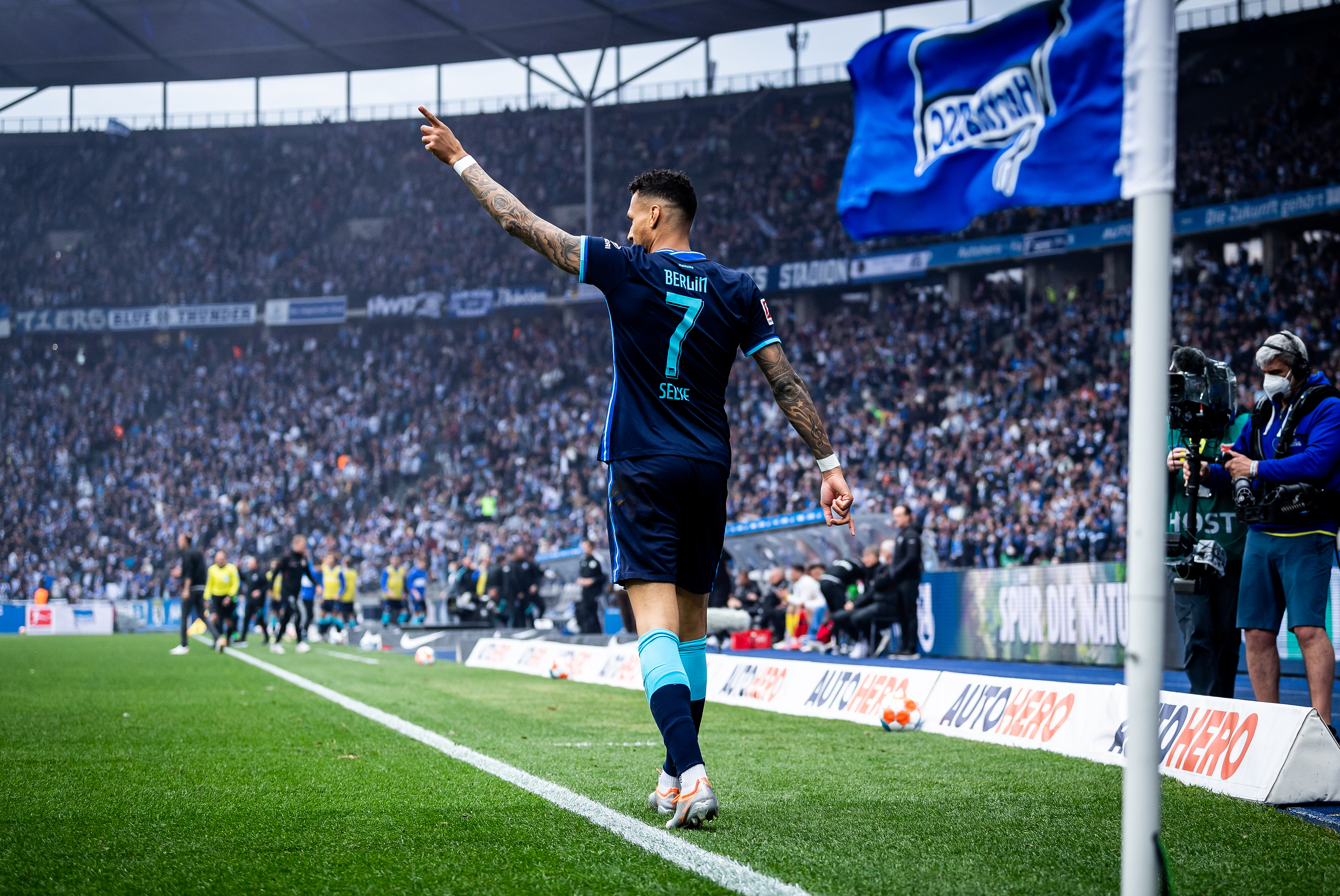 Davie Selke zeigt mit dem Finger Richtung Stadiondach.