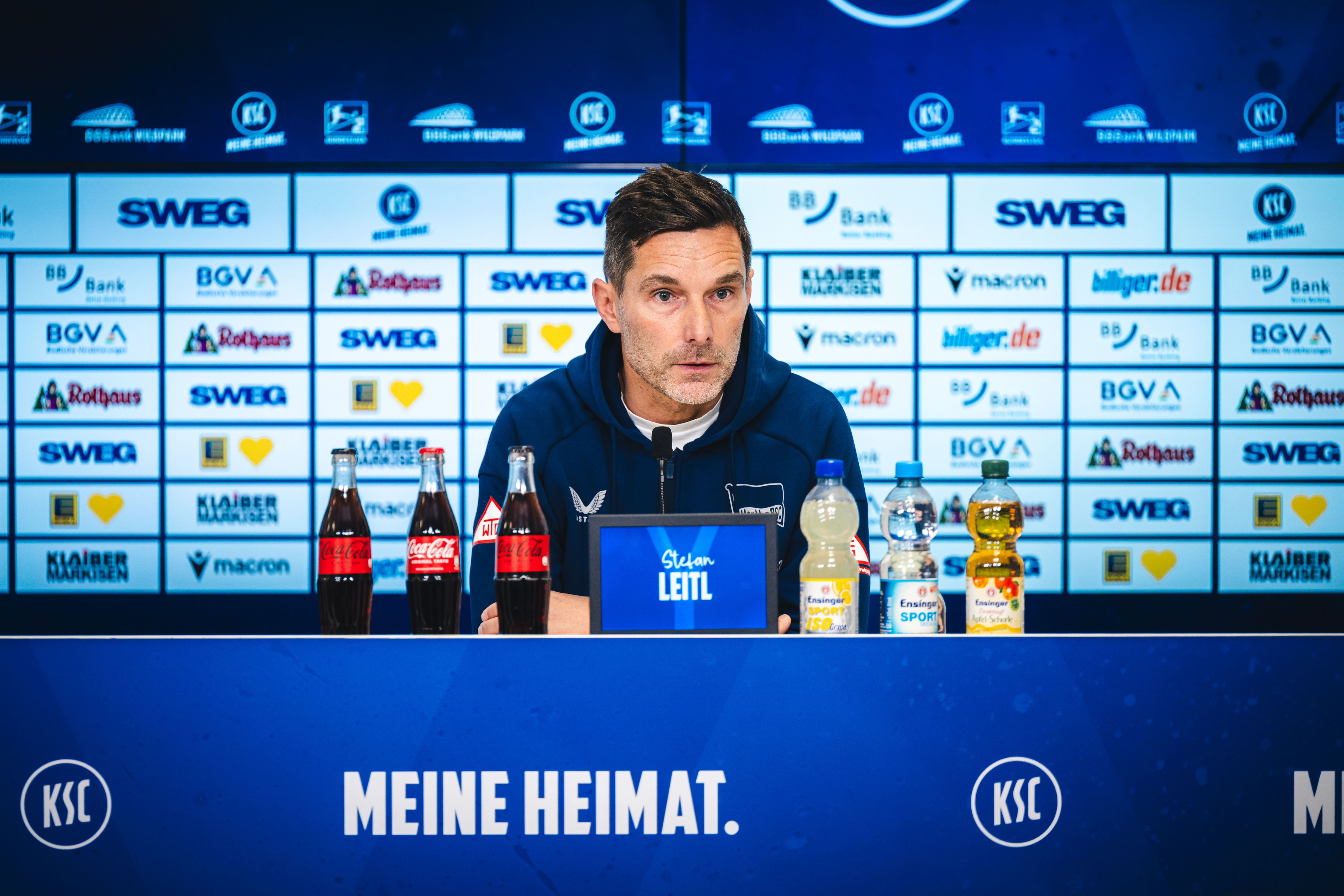 Stefan Leitl sitzt bei der Pressekonferenz auf dem Podium.